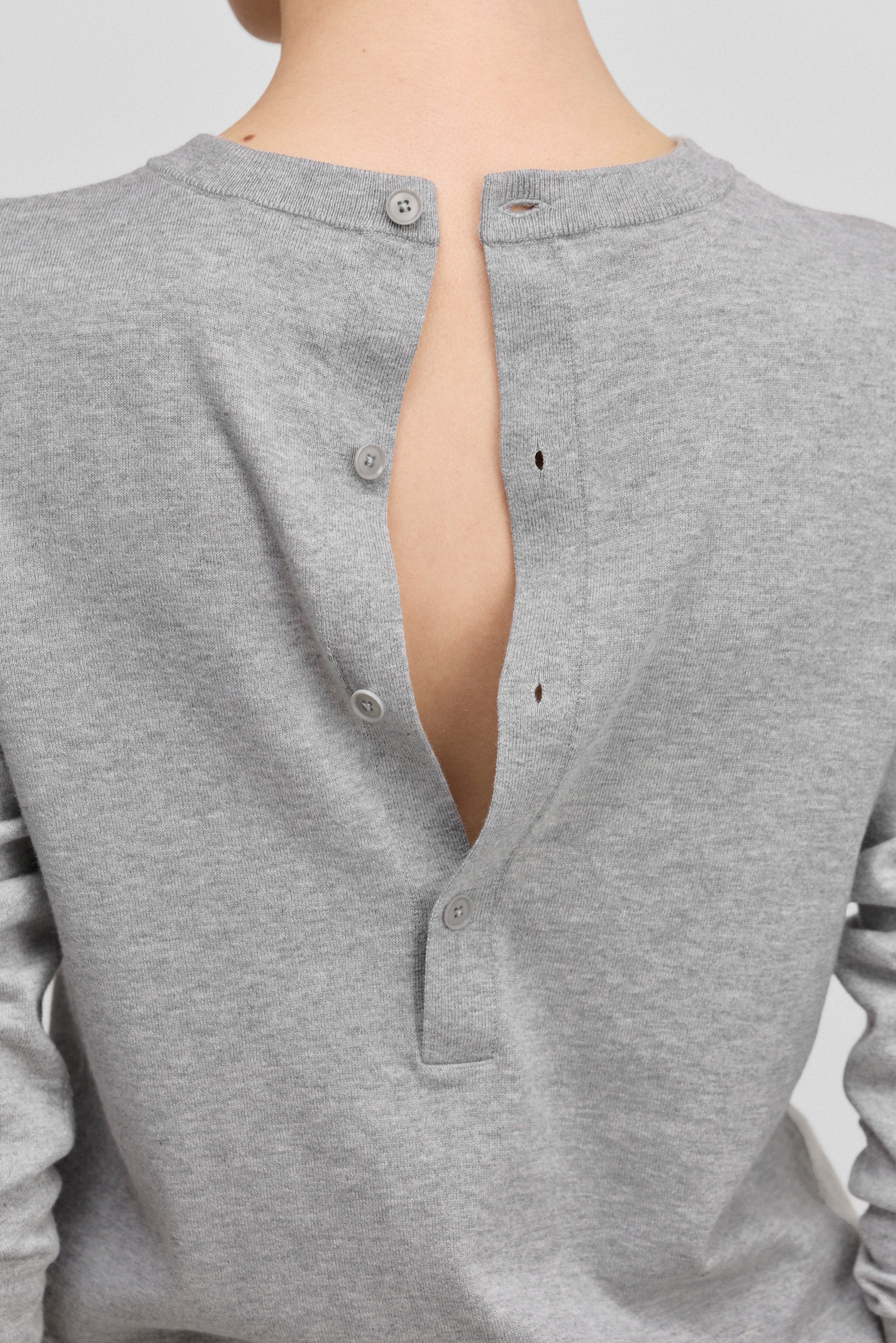 detail of the four corozo buttons on the back of a grey long-sleeved cotton cashmere top.
