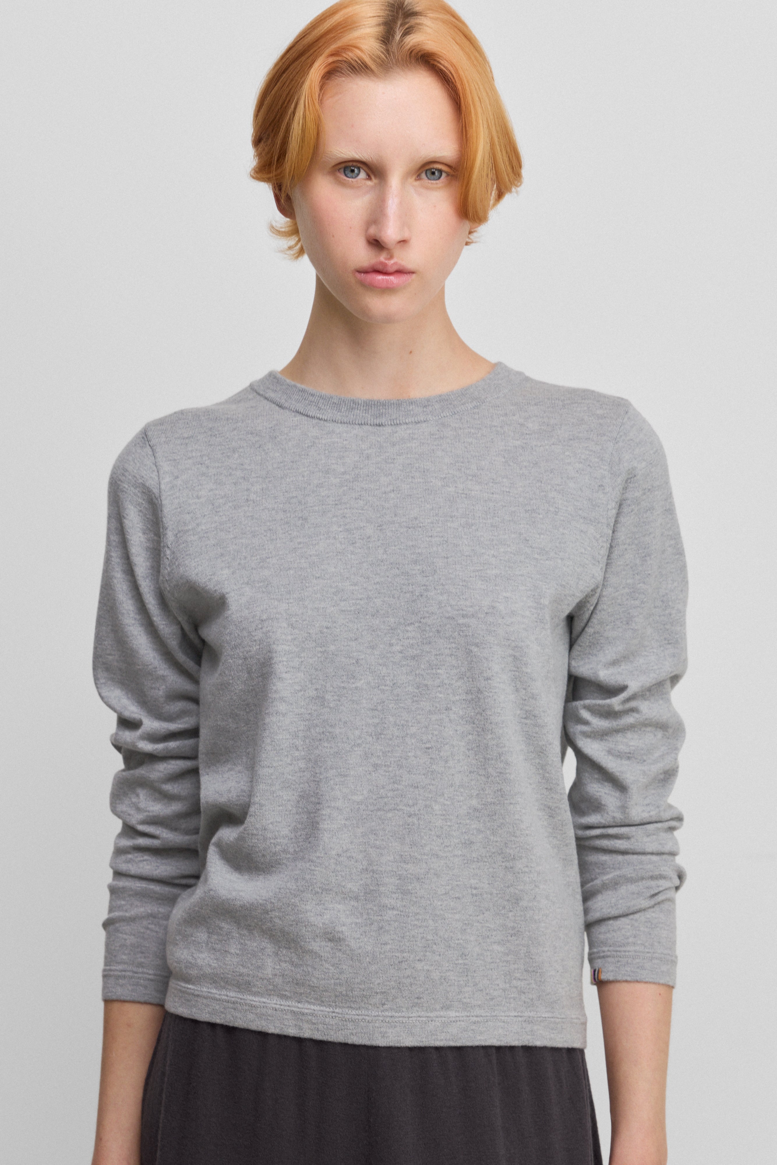 woman wearing a light grey cotton cashmere long-sleeved crew-neck top.
