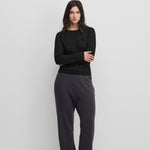 woman wearing dark grey loose-fit cashmere pants with raw-cut hems.