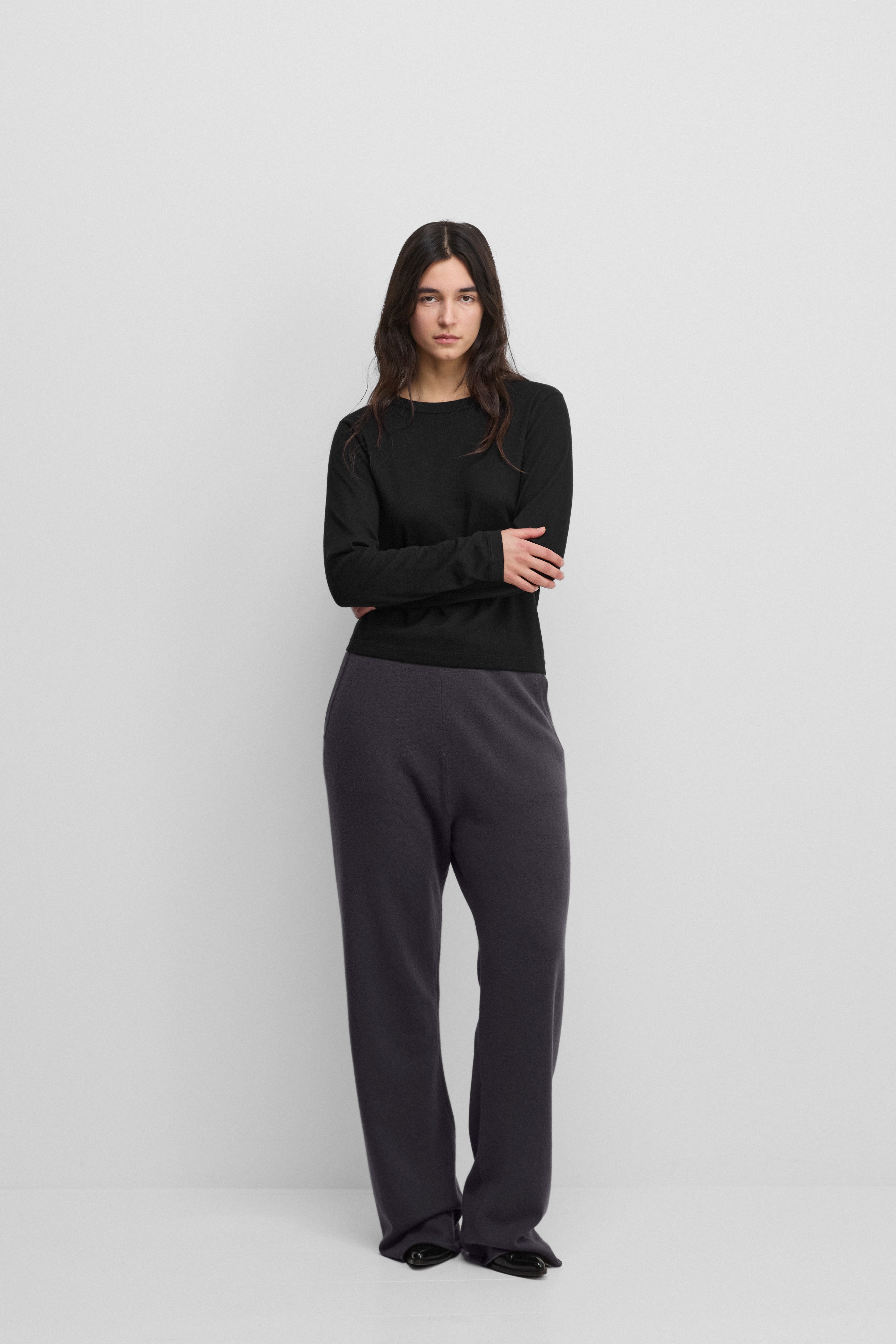 woman wearing dark grey loose-fit cashmere pants with raw-cut hems.