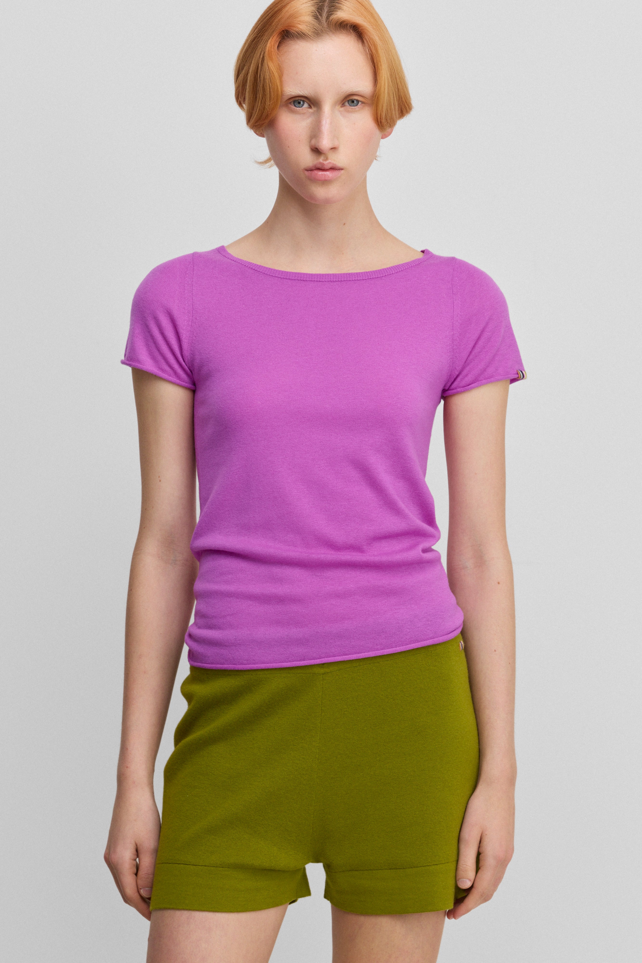 woman wearing a bright pink fitted wool cashmere t-shirt with a boat neck and short sleeves.