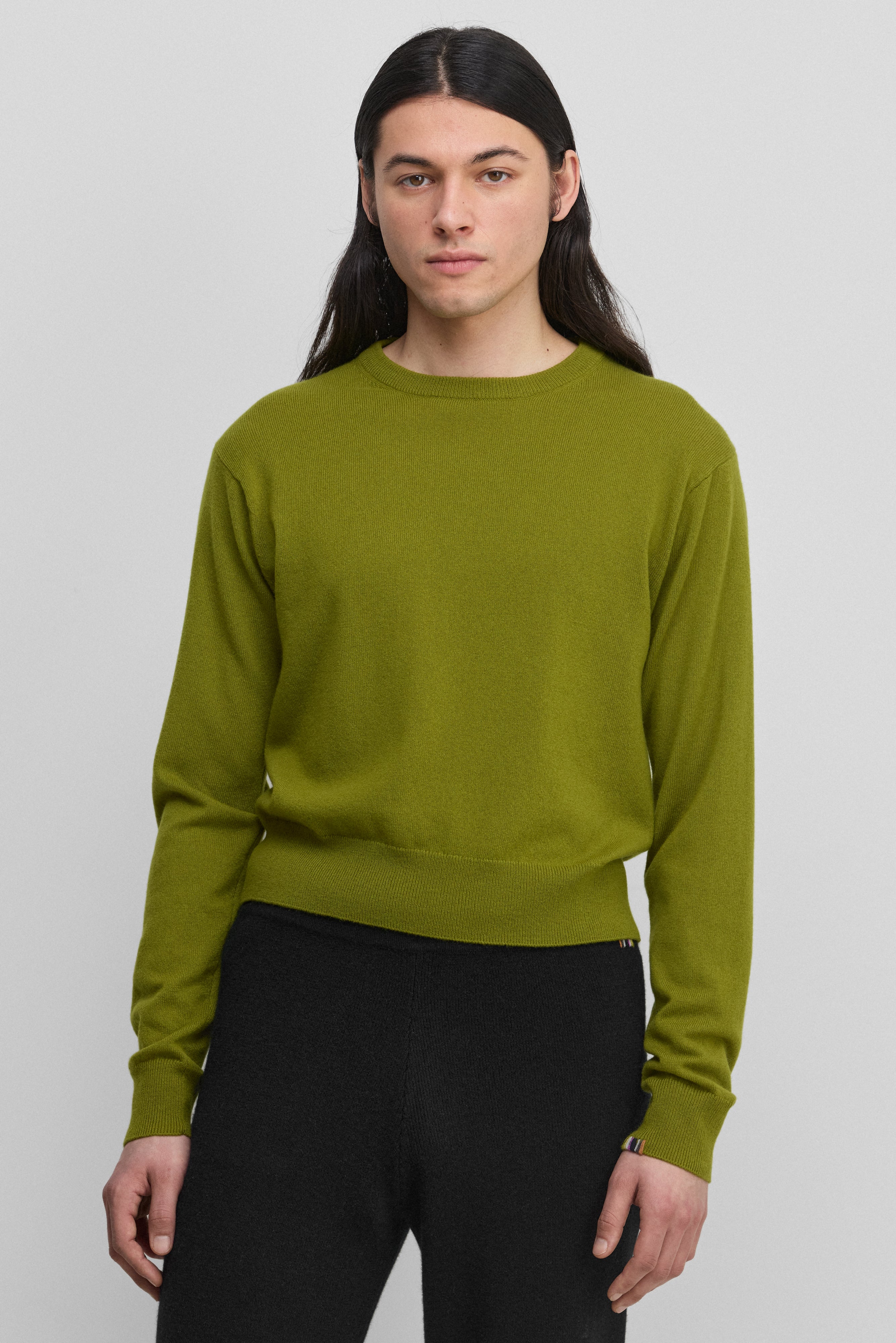 man wearing a green cashmere crew-neck sweater with ribbed hem, cuffs, neckline.