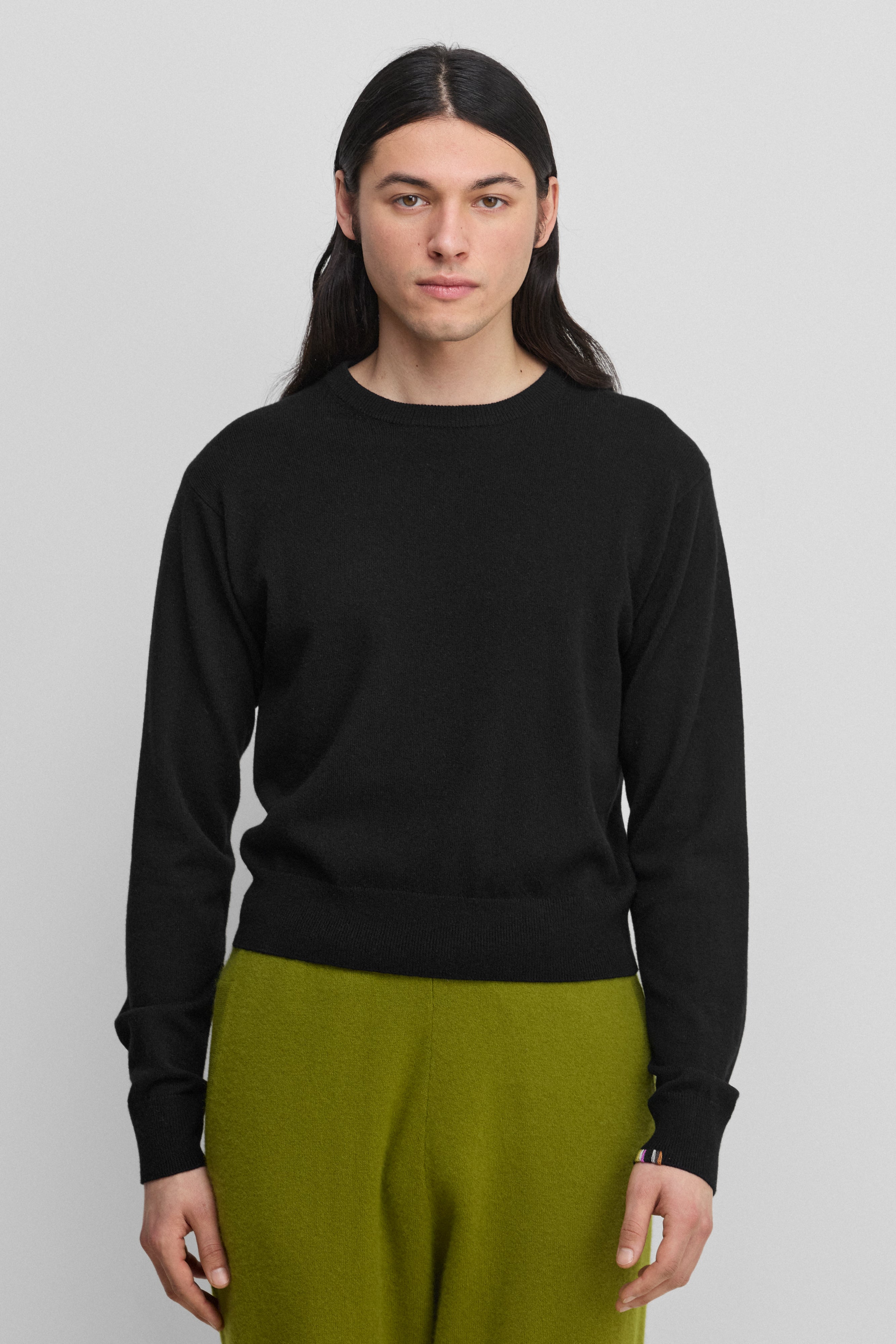 man wearing a black cashmere crew-neck sweater with ribbed hem, cuffs, neckline.