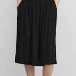 woman wearing a black cotton cashmere midi skirt with an elasticated waistband and two side pockets.