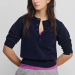 woman wearing a navy blue half-button cashmere sweater with elbow-length sleeves and ribbed hem and cuffs.