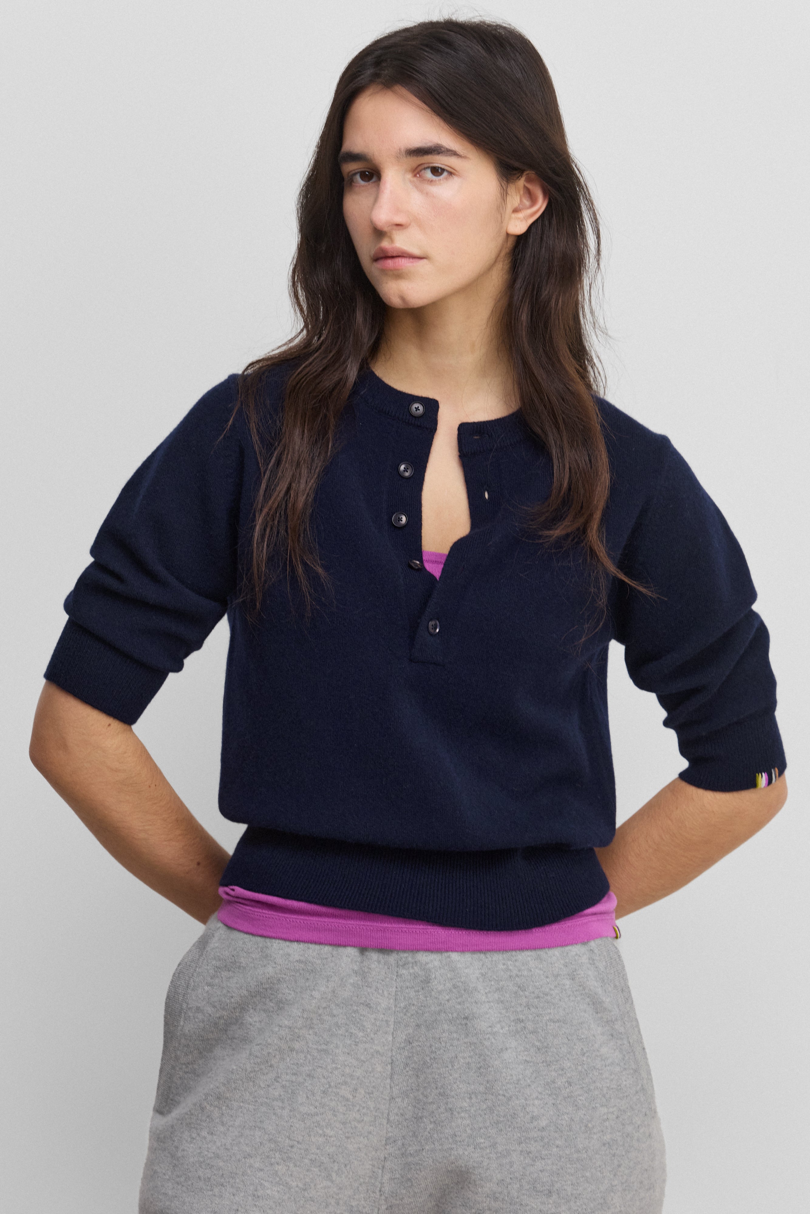woman wearing a navy blue half-button cashmere sweater with elbow-length sleeves and ribbed hem and cuffs.