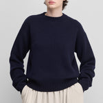 woman wearing a loose-fit navy blue cashmere crew-neck sweater with ribbed trims.