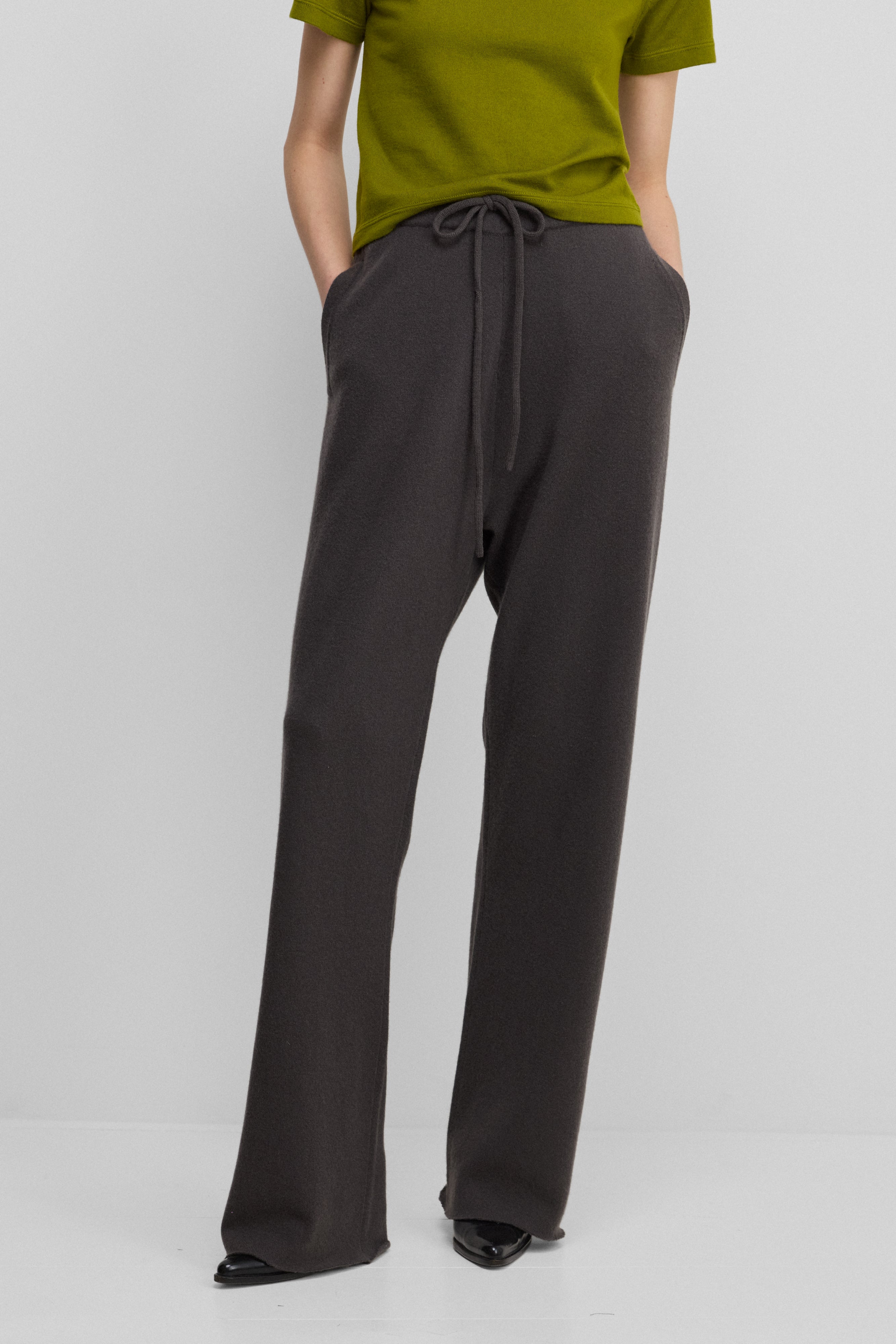 woman wearing dark grey loose-fit cashmere pants with a drawstring waistband and side pockets.