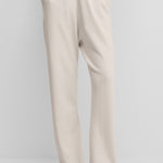 woman wearing white loose-fit cashmere pants with a drawstring waistband and side pockets.