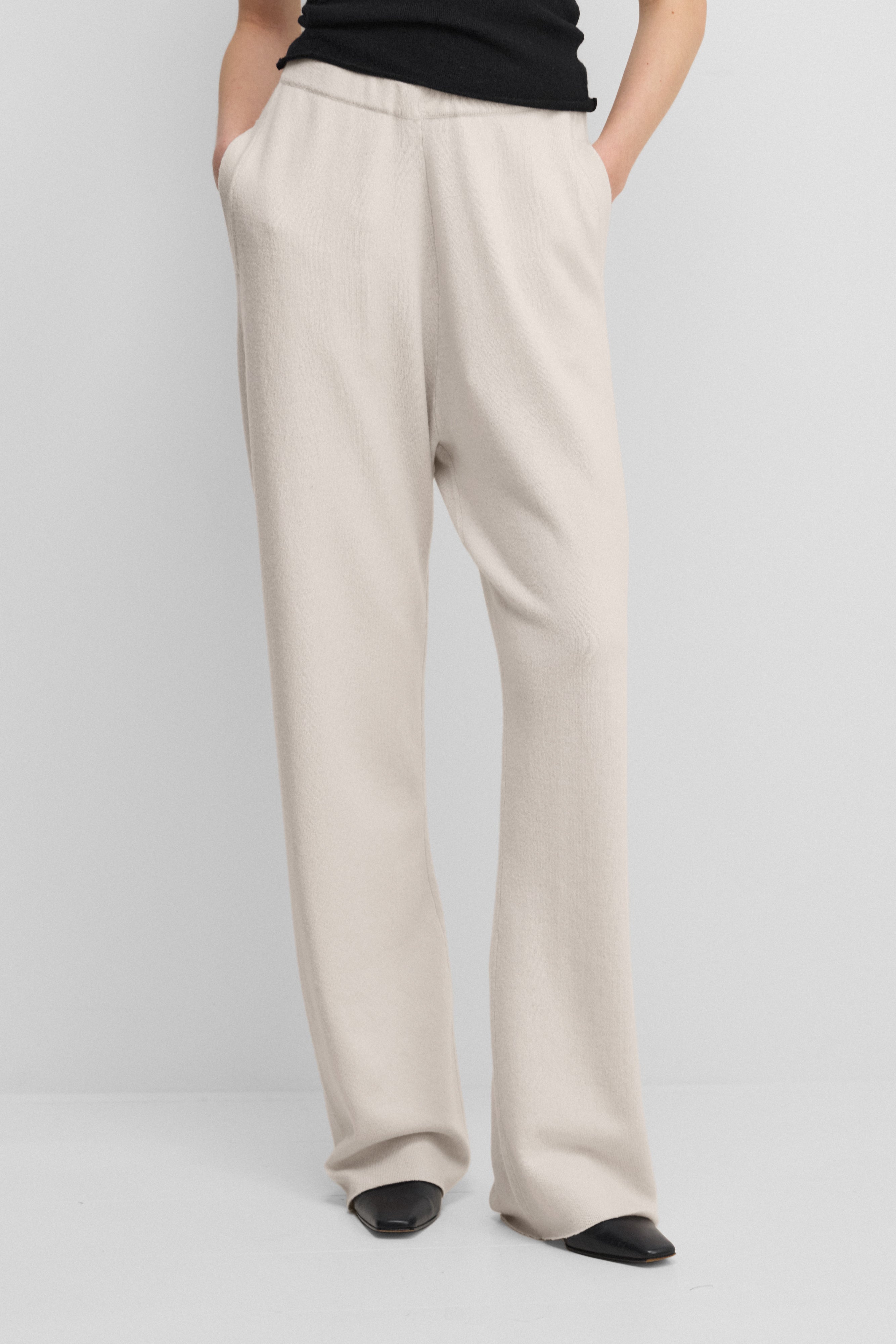 woman wearing white loose-fit cashmere pants with a drawstring waistband and side pockets.