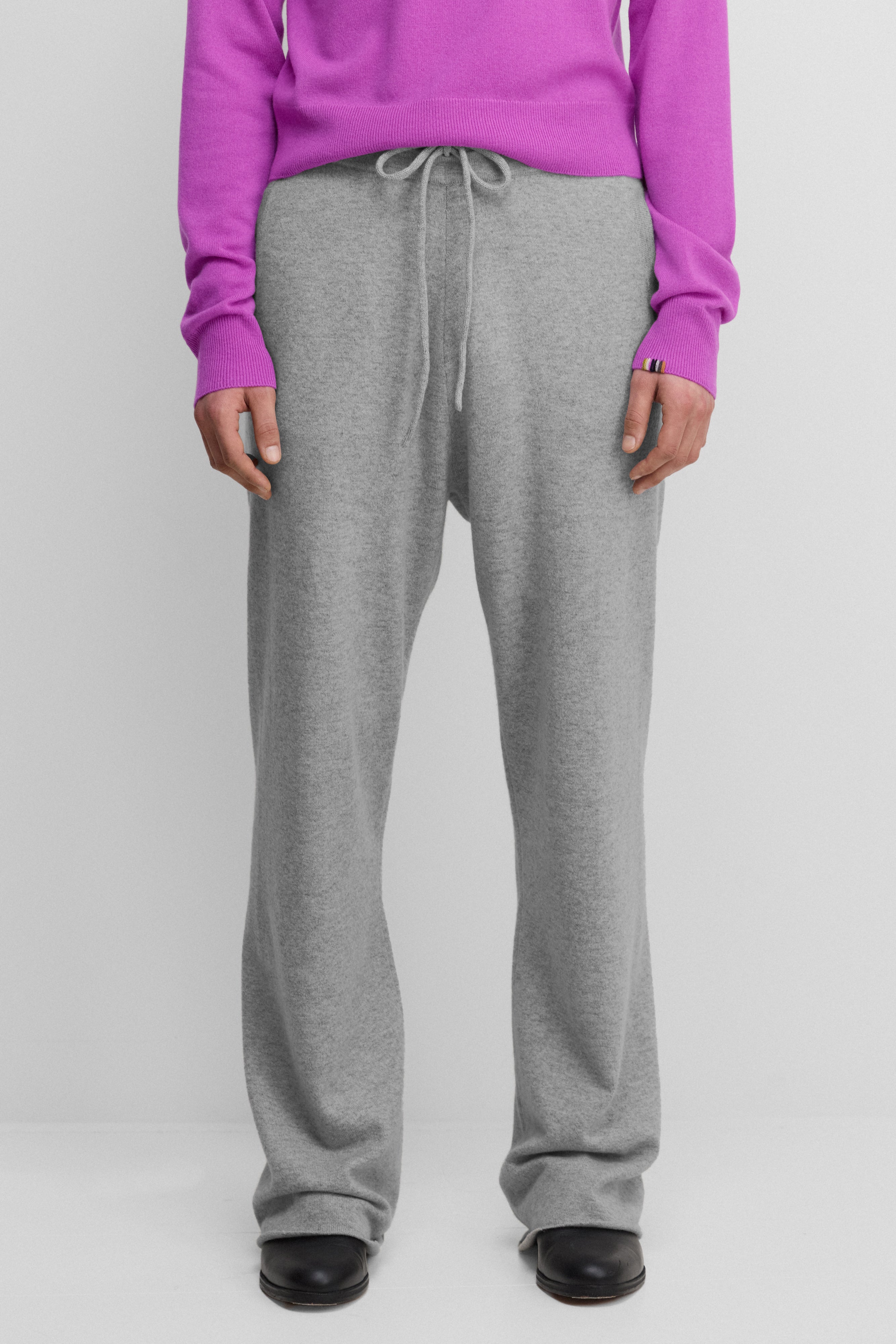 model wearing grey loose-fit cashmere pants with a drawstring waistband.
