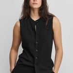 woman wearing a black sleeveless cotton-cashmere vest with corozo buttons and a crewneck.