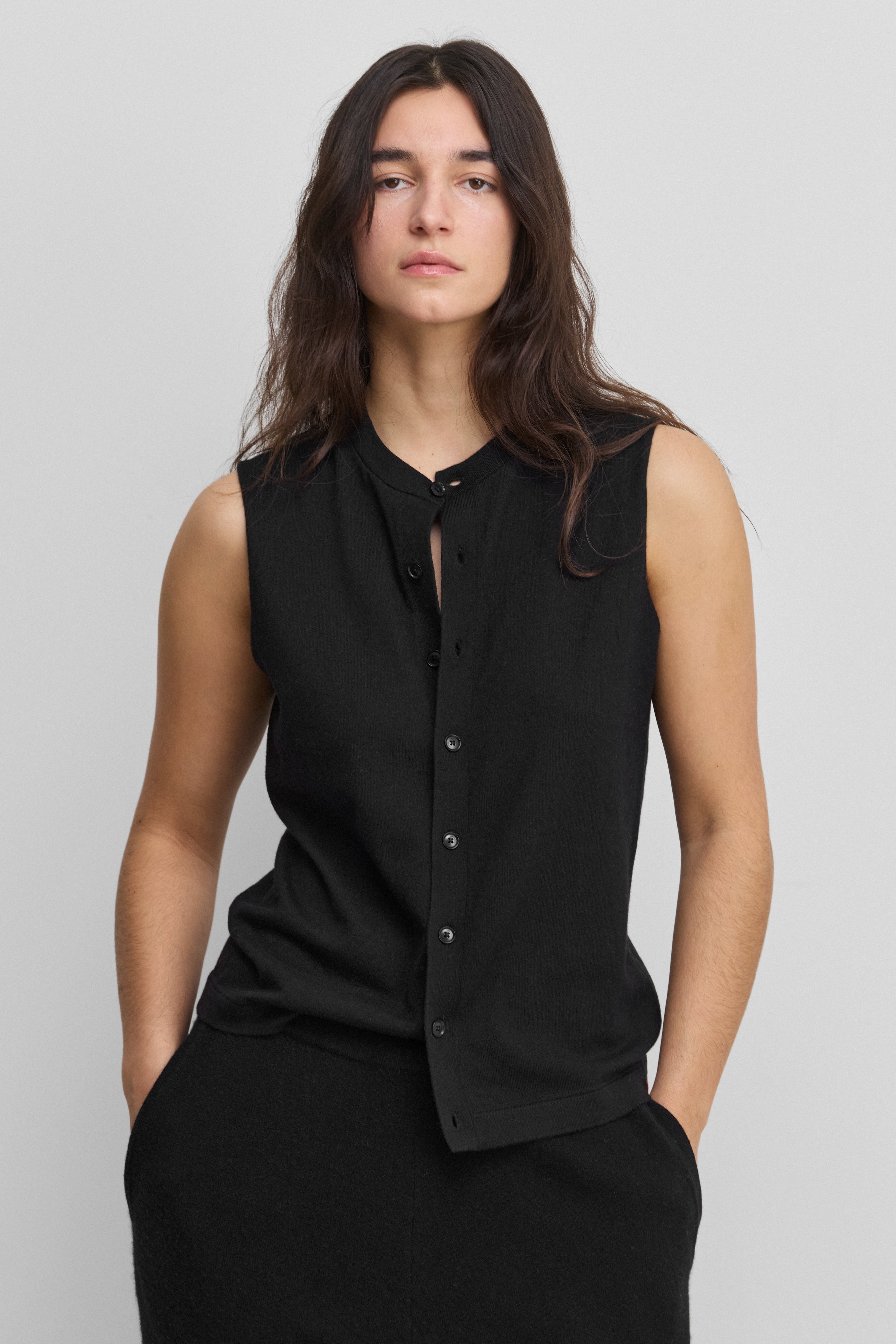 woman wearing a black sleeveless cotton-cashmere vest with corozo buttons and a crewneck.