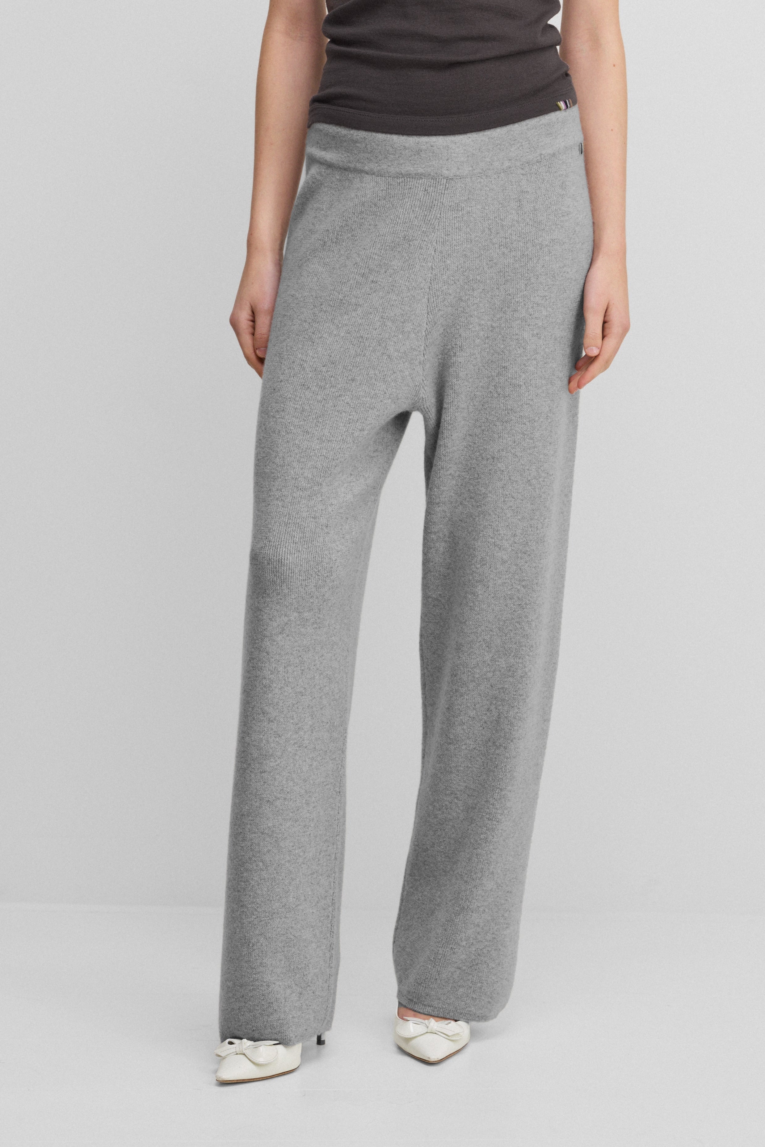woman wearing grey rib-knit cashmere pants with a drawstring waistband and straight legs.