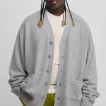 man wearing a grey oversized chunky cashmere button-up cardigan with pockets and ribbed hem and cuffs.