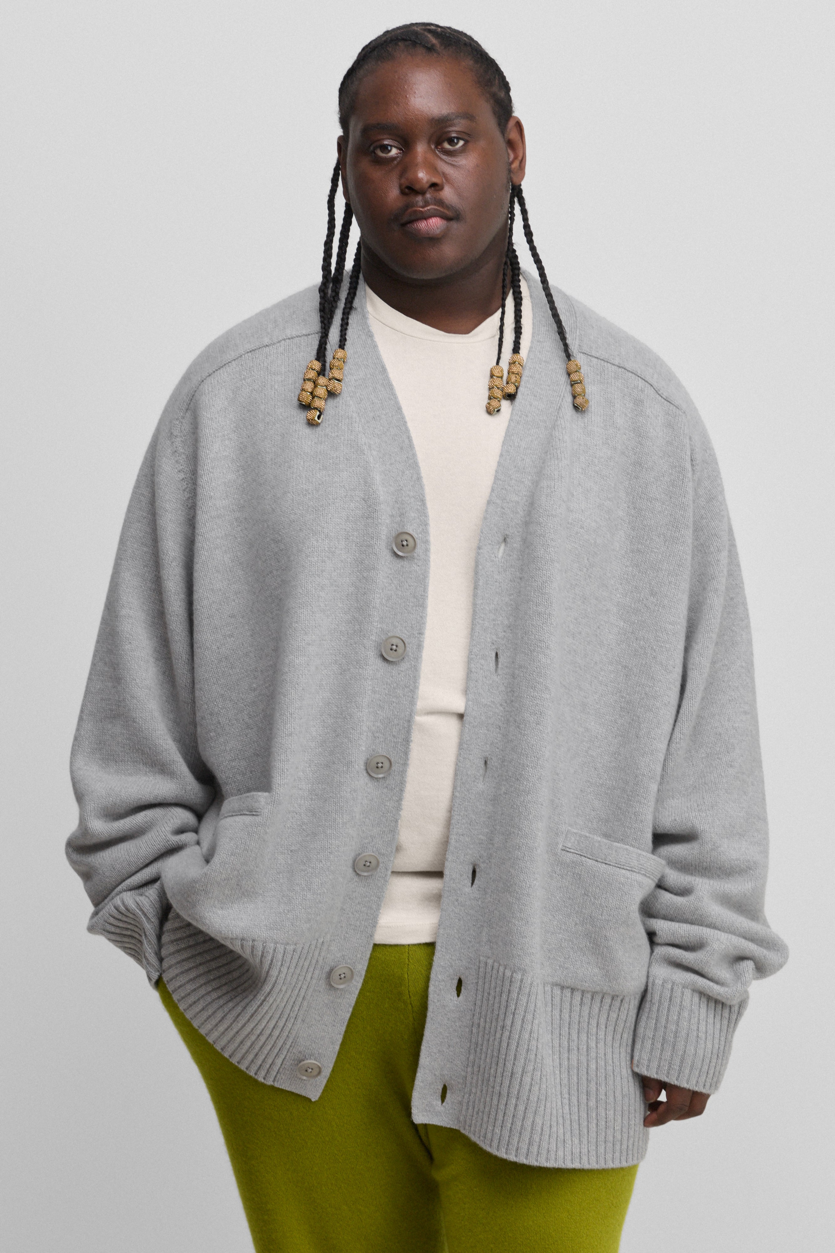 man wearing a grey oversized chunky cashmere button-up cardigan with pockets and ribbed hem and cuffs.