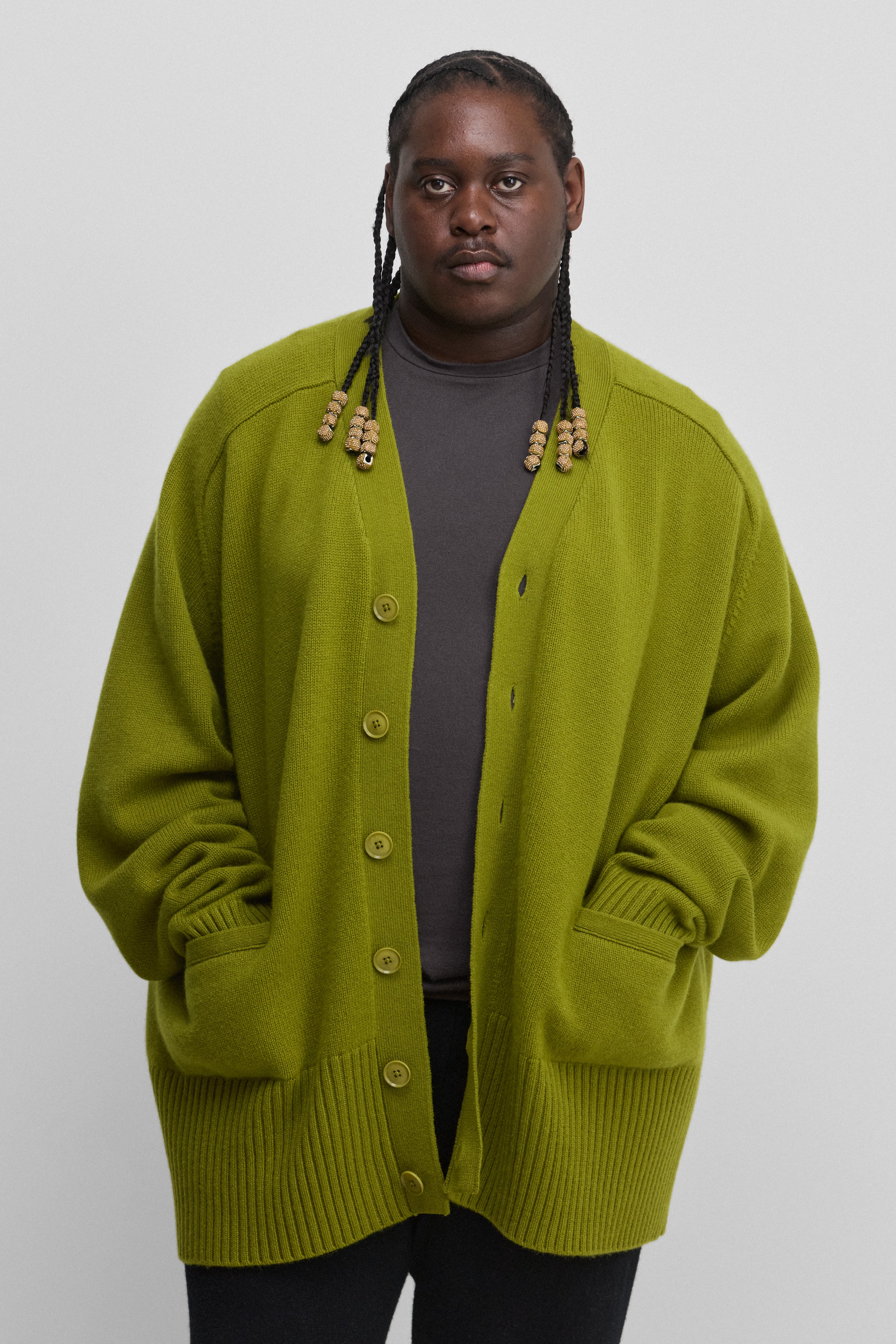 man wearing a green oversized chunky cashmere cardigan with six corozo buttons, v-neck and pockets.
