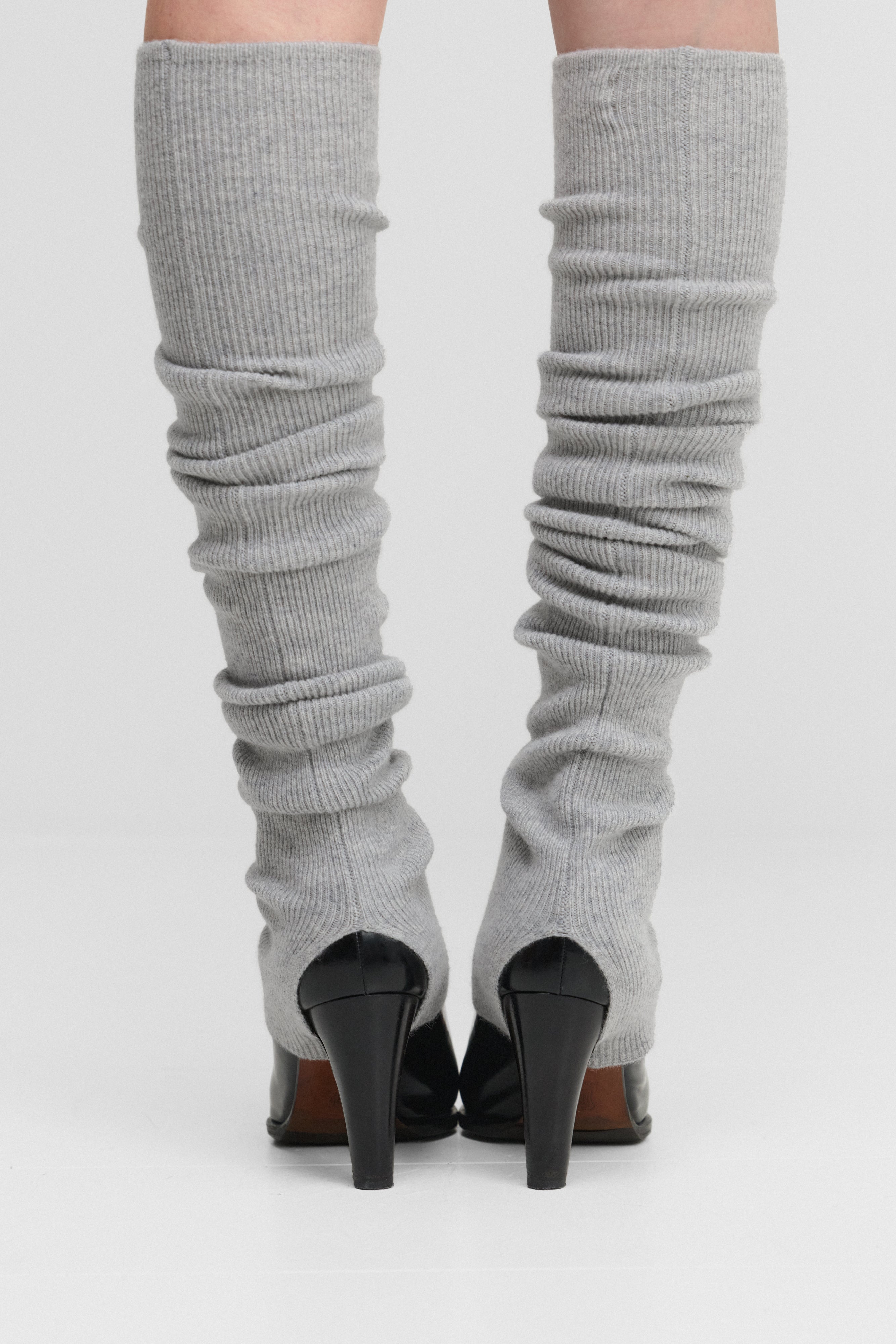 woman wearing light grey rib-knit cashmere leg warmers, styled with heels.