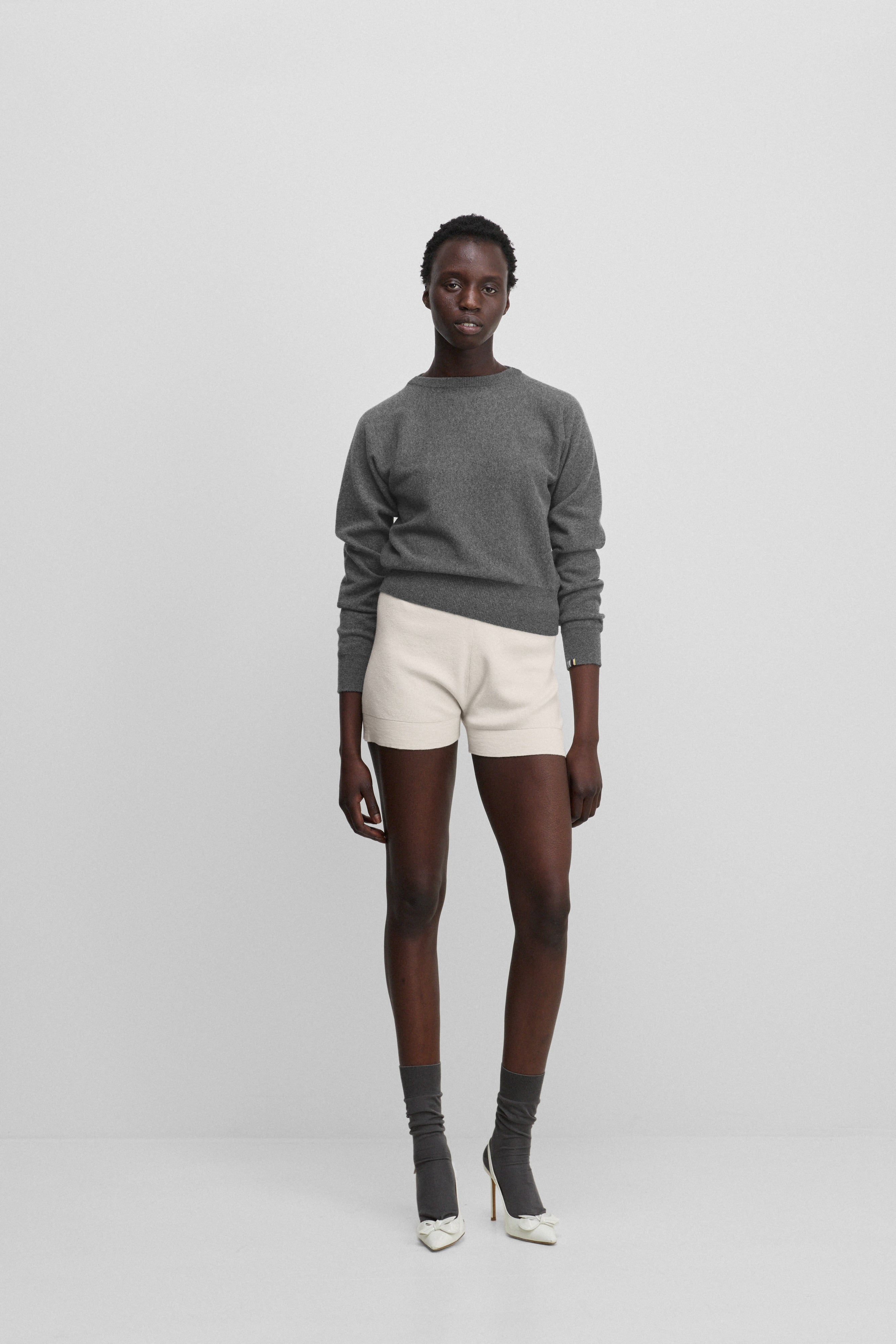woman wearing white cotton cashmere rib-knit shorts, styled with a grey sweater.