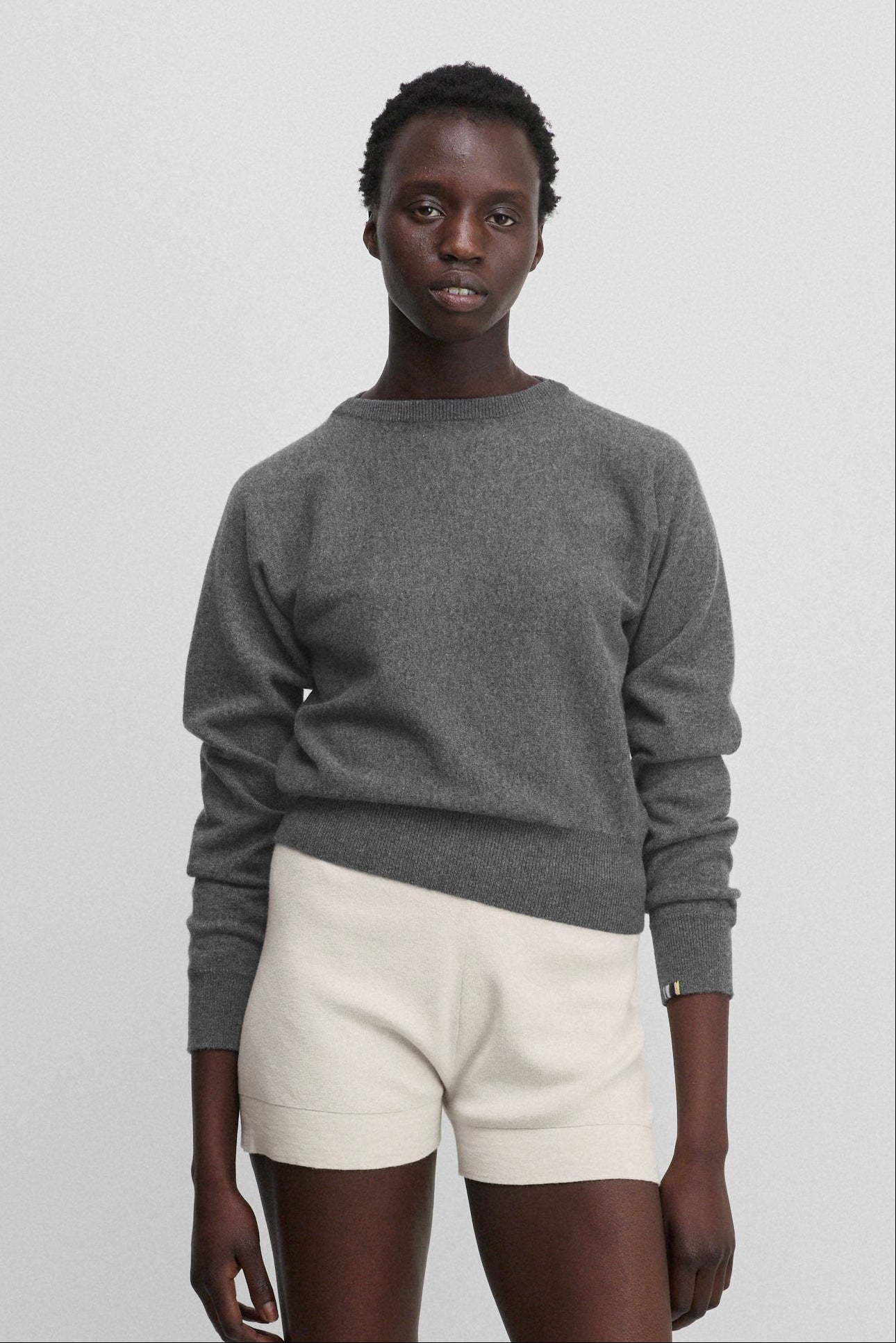 woman wearing a petite dark grey cashmere sweater with bat sleeves.