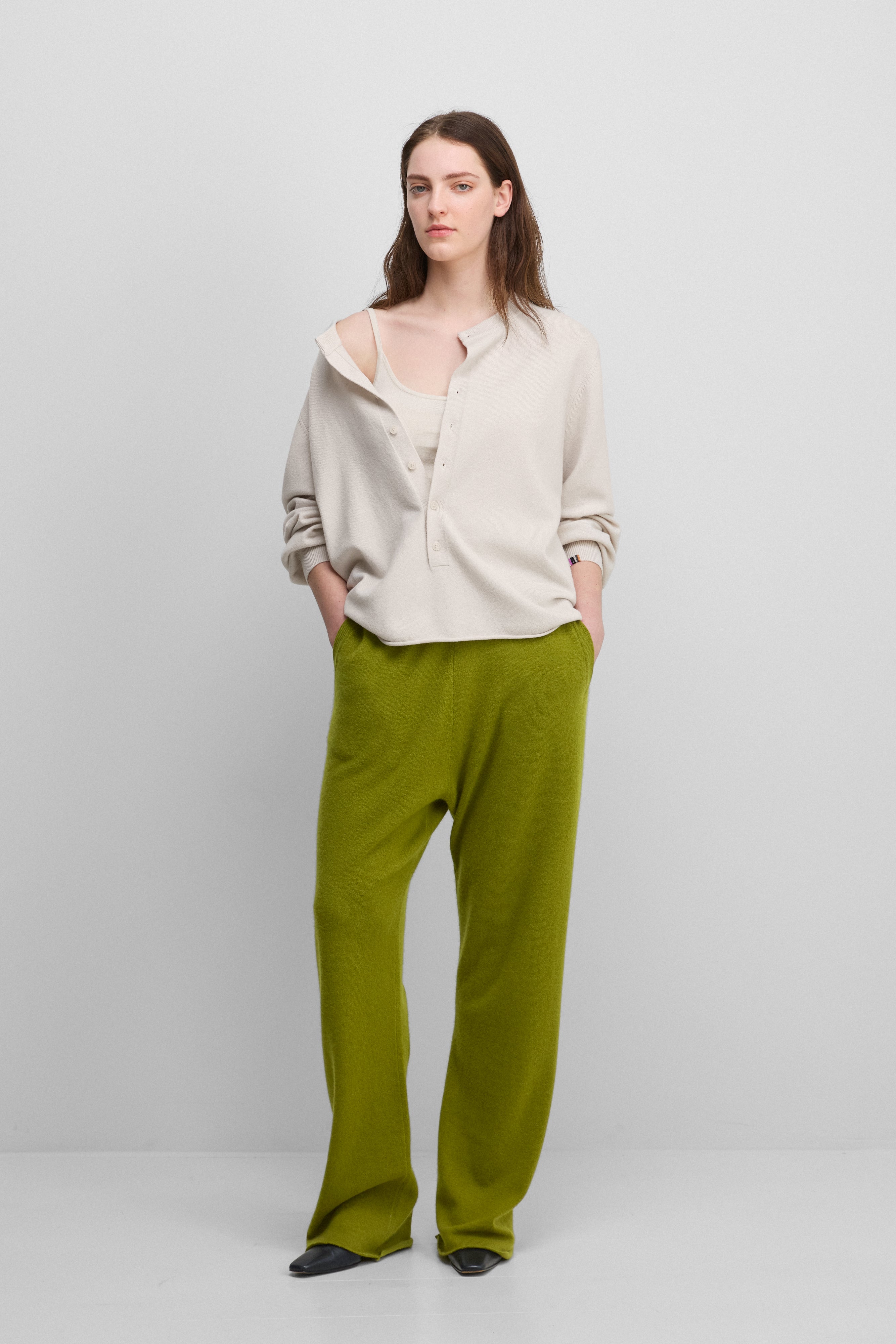 woman wearing green loose-fit cashmere pants with two side pockets.