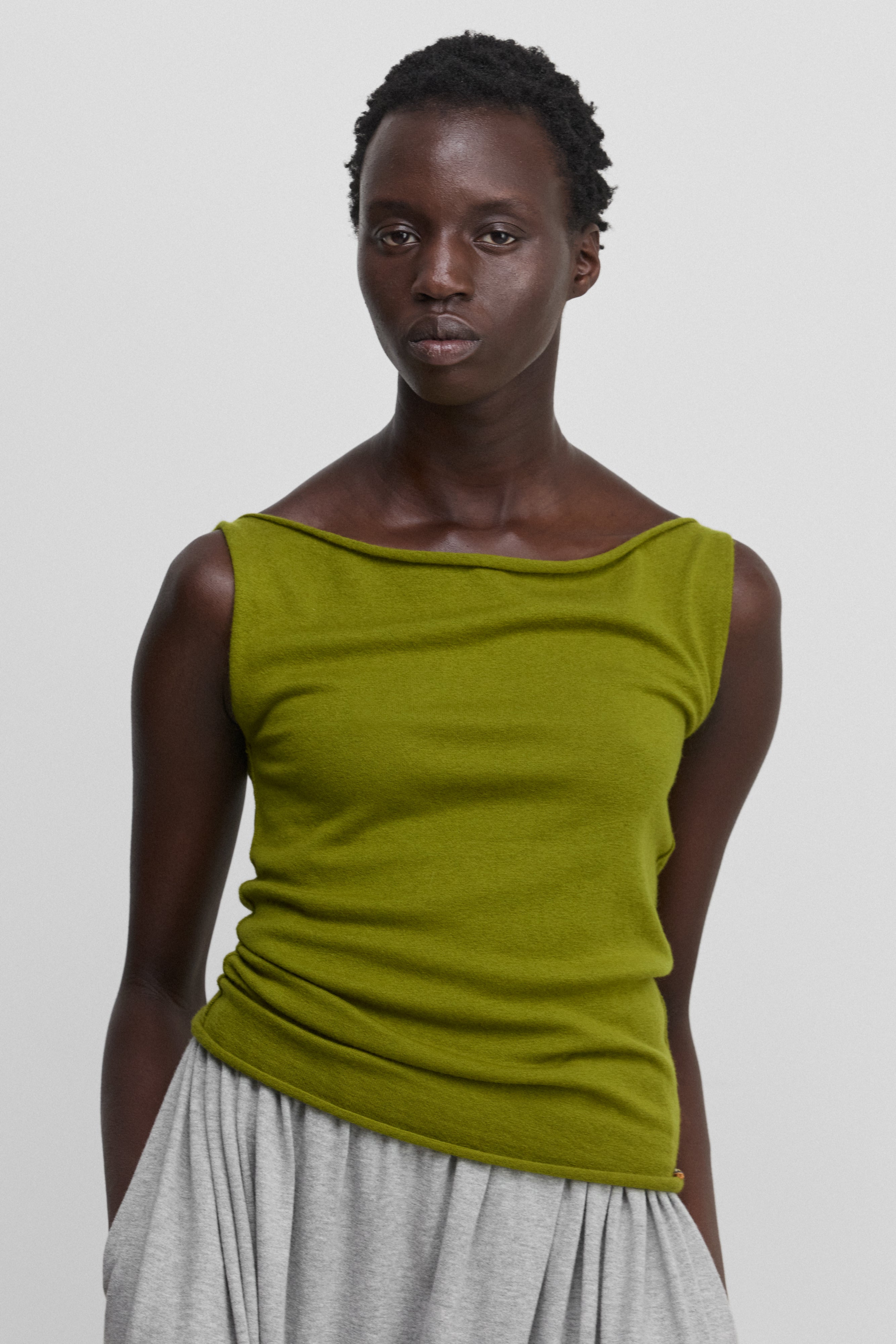 woman wearing a green sleeveless wool cashmere top with a boat neck.