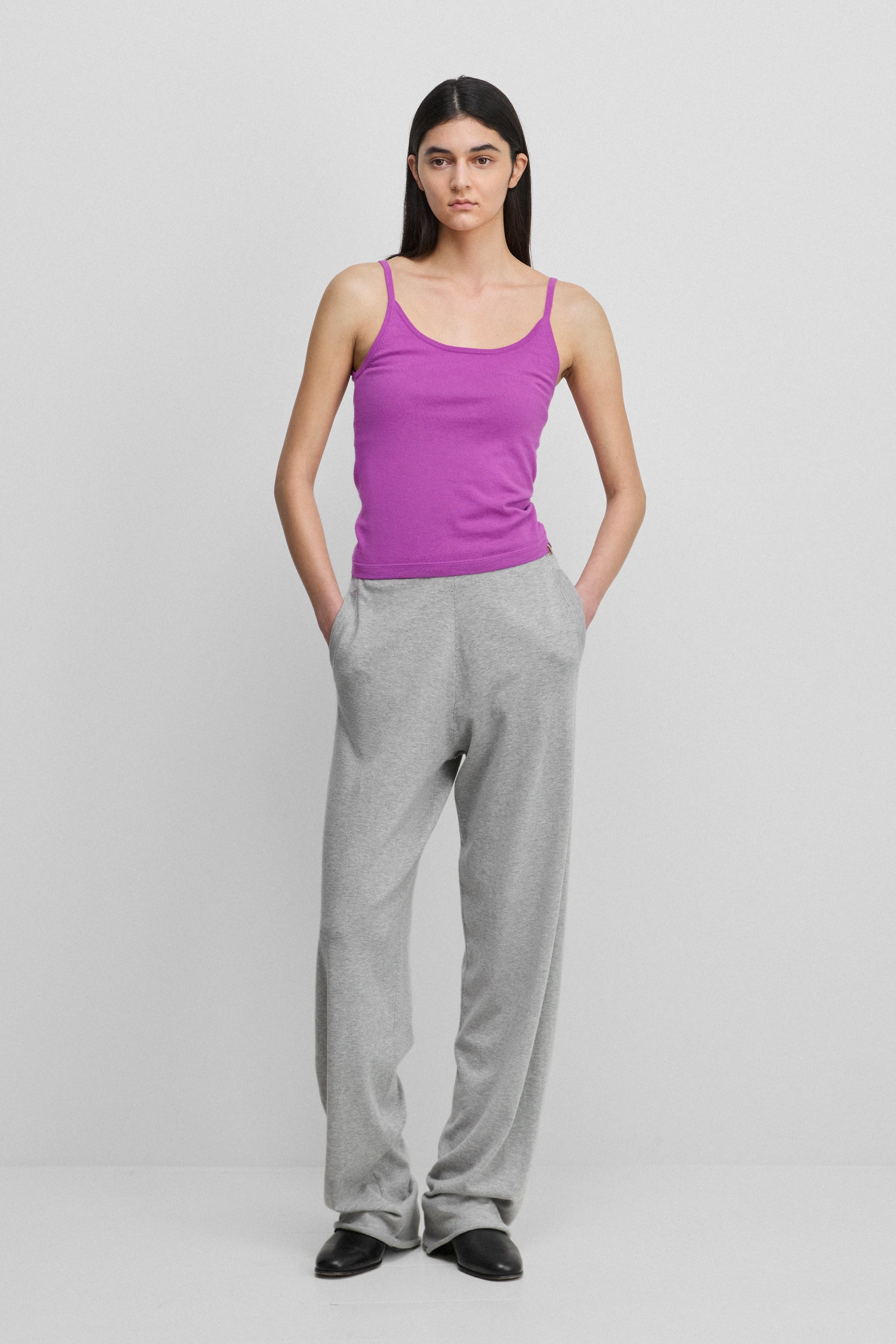 woman wearing loose-fit grey cotton cashmere pants with side pockets, styled with a pink top.