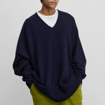 man wearing a navy blue oversized cashmere v-neck sweater with ribbed hem and cuffs.