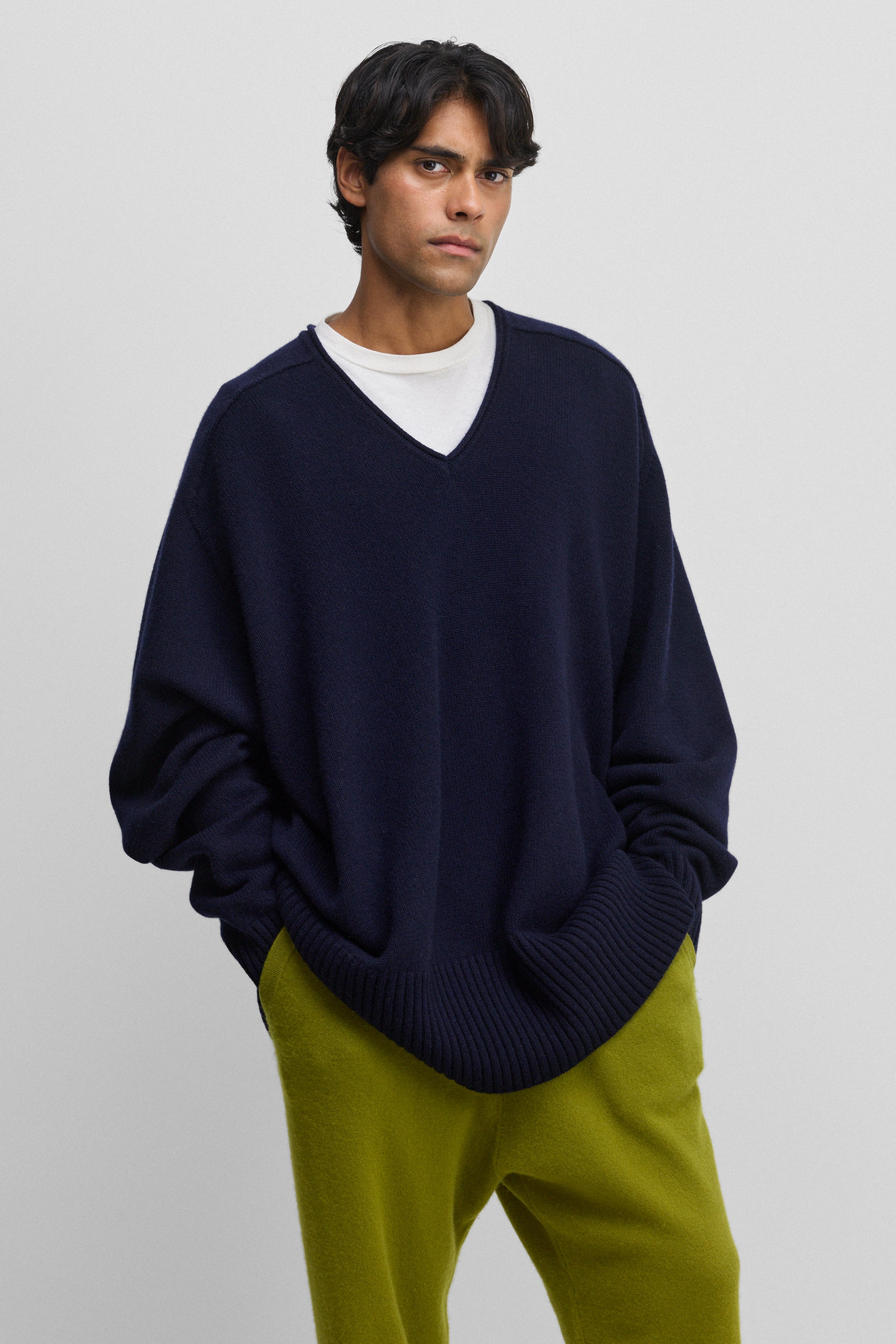 man wearing a navy blue oversized cashmere v-neck sweater with ribbed hem and cuffs.