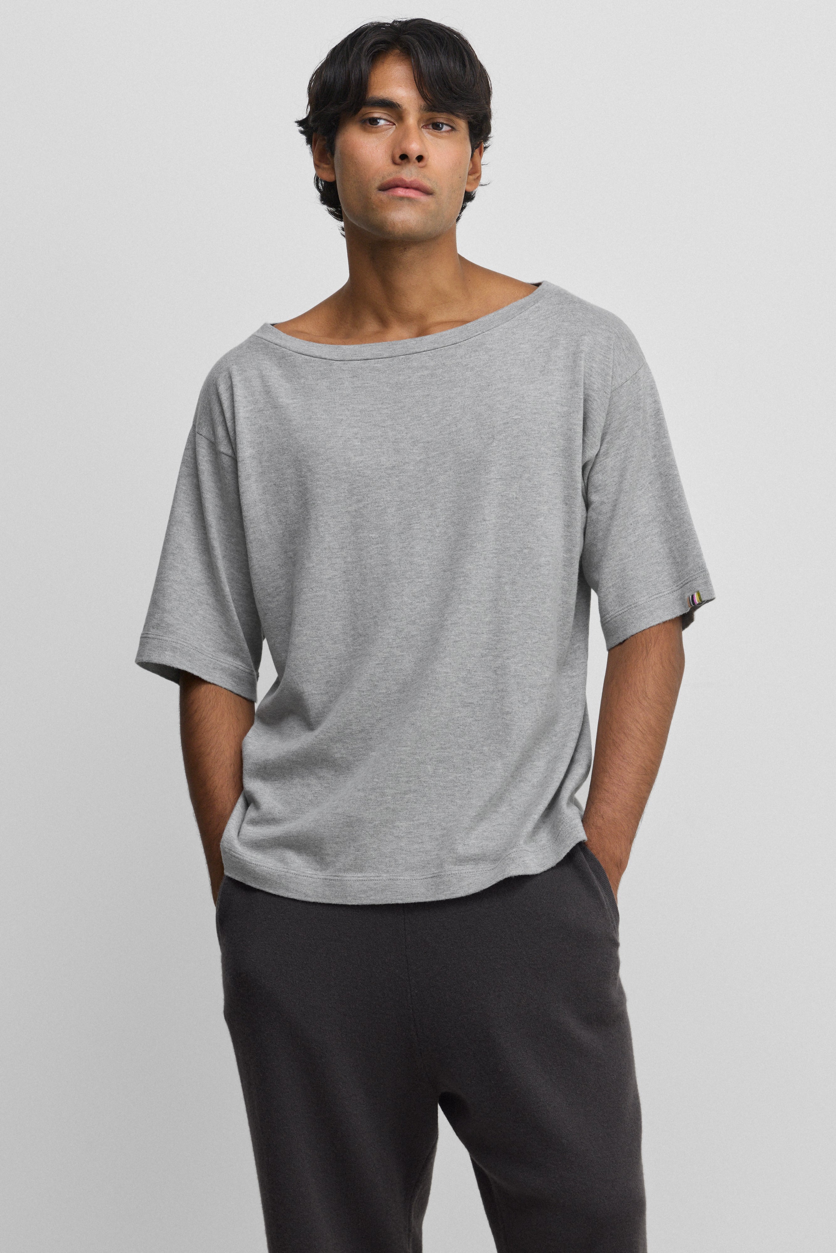 man wearing an oversized grey cotton cashmere t-shirt with a boat neck and elbow-length sleeves.