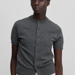 woman wearing a dark grey short-sleeved cashmere button-up cardigan with rib-knitted hem and cuffs.