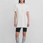 woman wearing a white cotton-cashmere mini t-shirt dress, styled with black biker shorts.