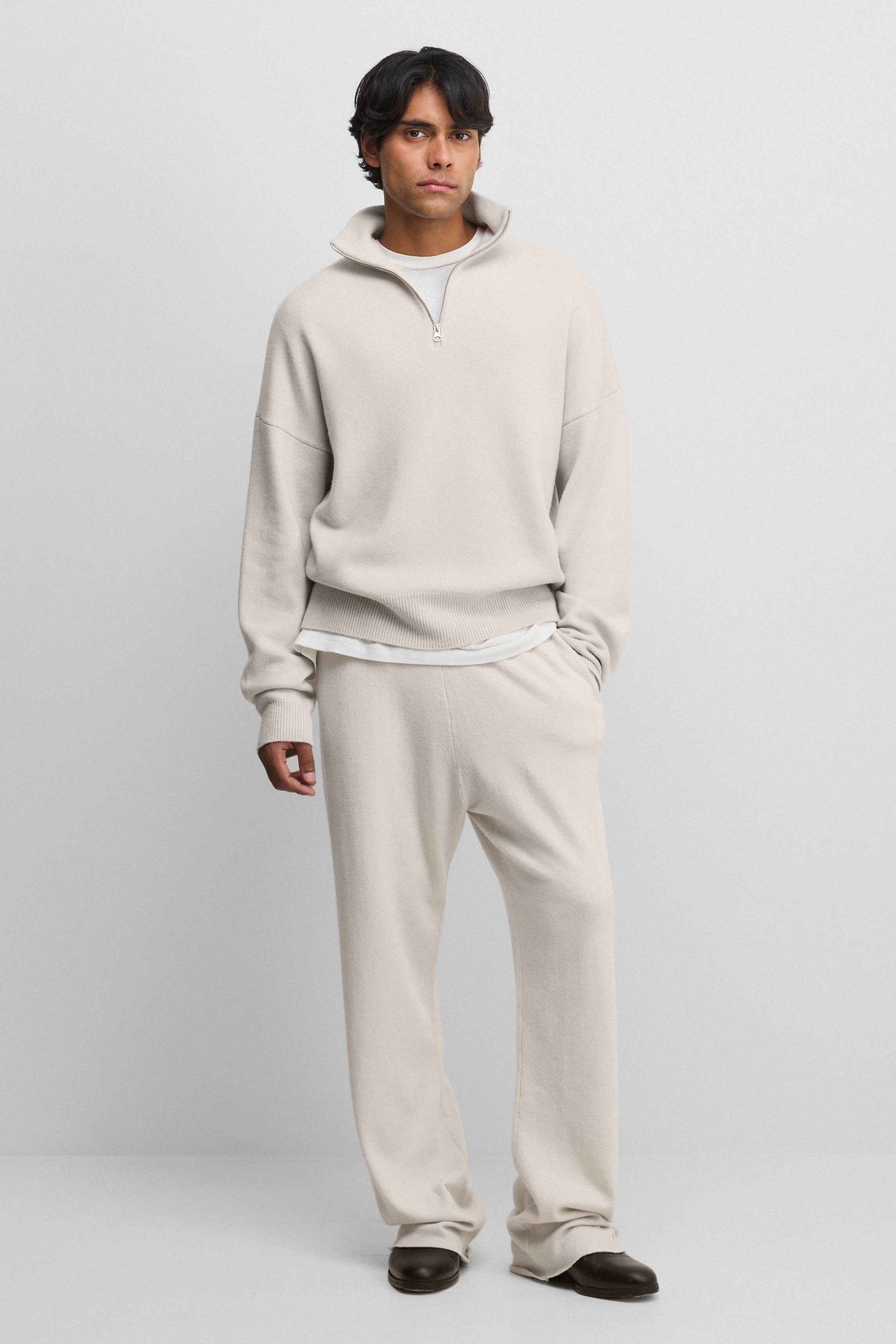 man wearing off-white loose-fit cashmere pants with two side pockets.