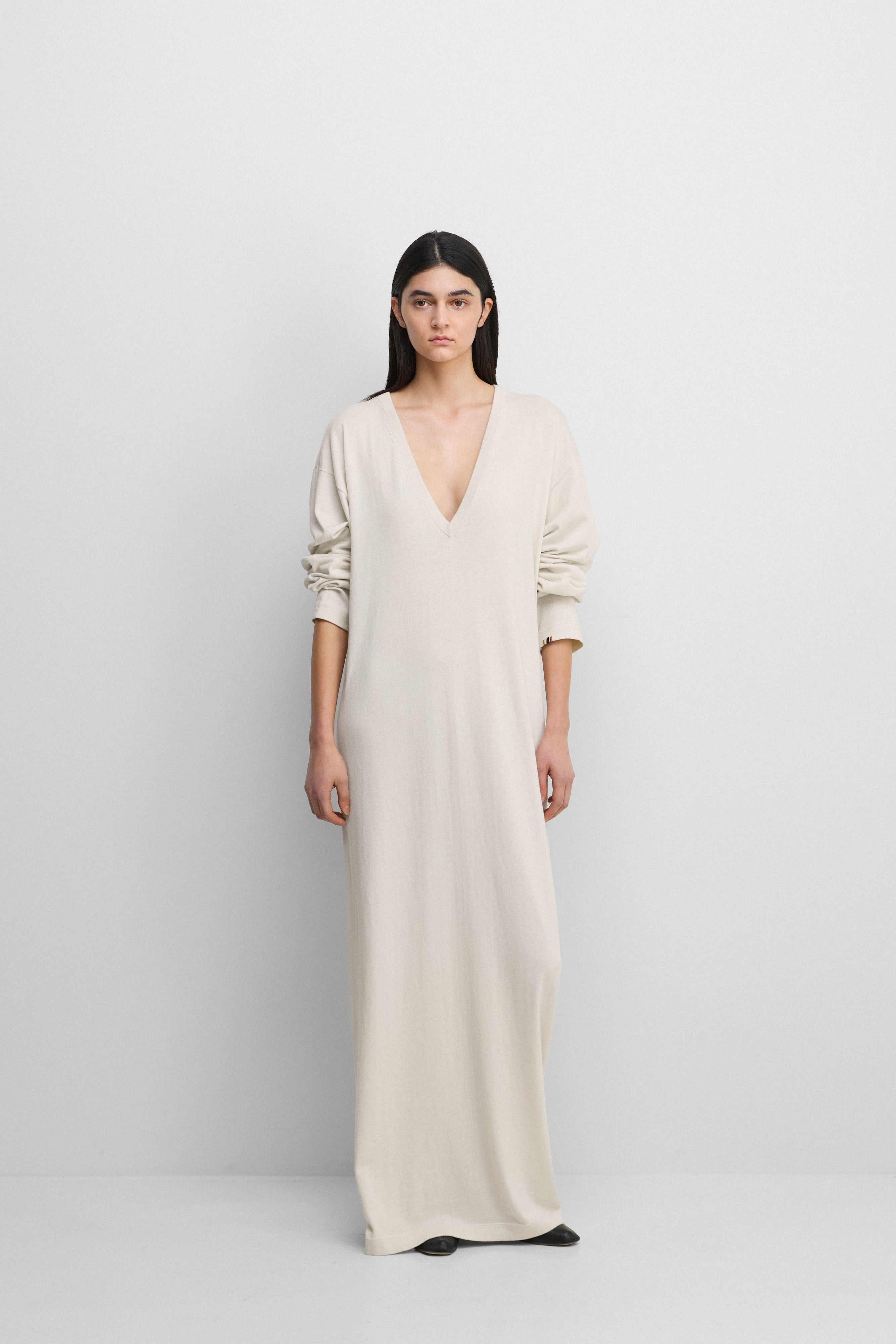 woman wearing a white long-sleeved cotton-cashmere maxi dress with a deep v-neck.