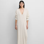 woman wearing a white long-sleeved cotton-cashmere maxi dress with a deep v-neck.