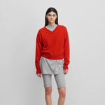 woman wearing a bright red classic-fit cashmere v-neck sweater, styled with grey biker shorts.