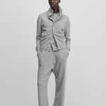 woman wearing a light grey cashmere button-up cardigan with a rib-knitted collar, styled with grey pants.