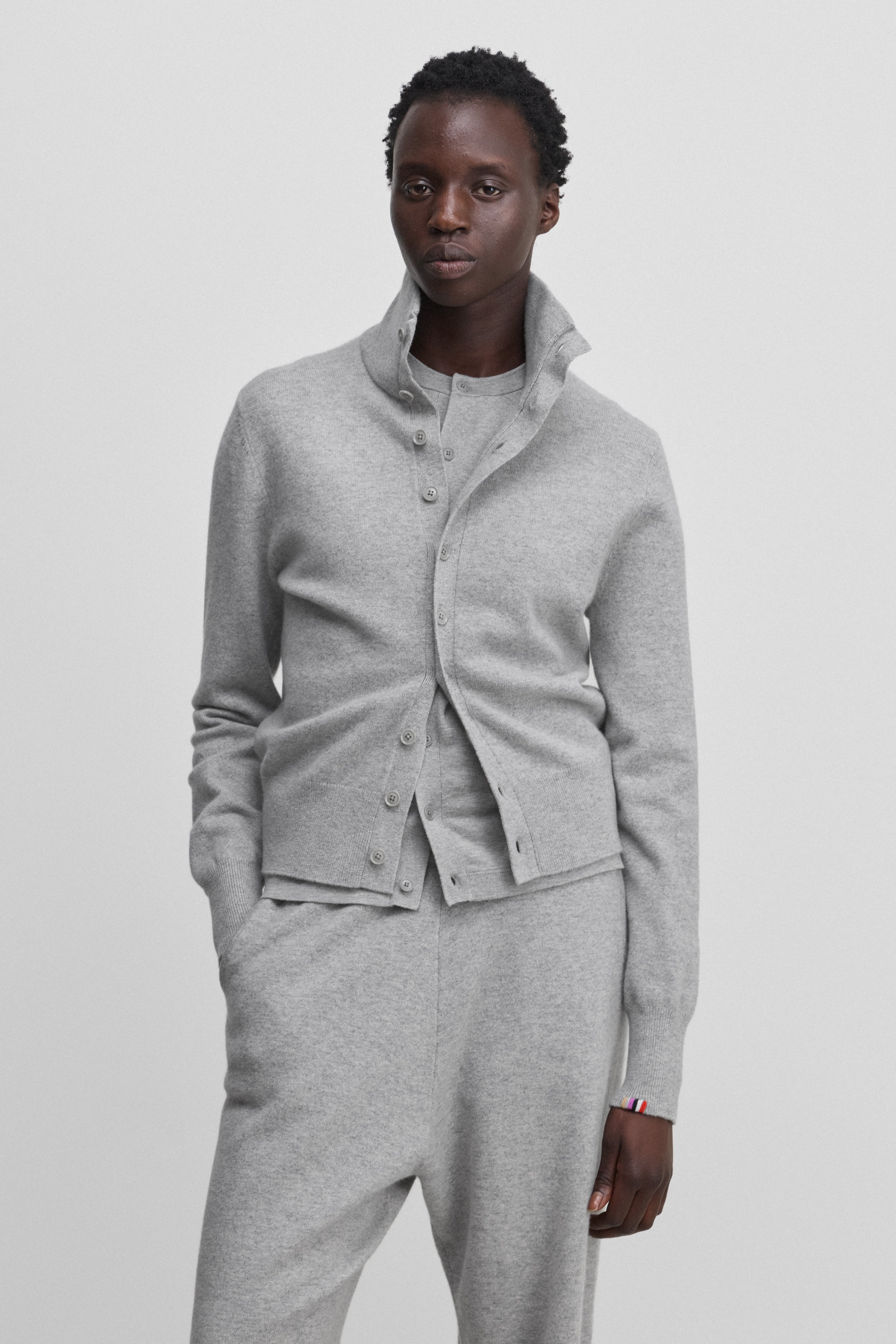 woman wearing a light grey cashmere button-up cardigan with a rib-knitted collar.