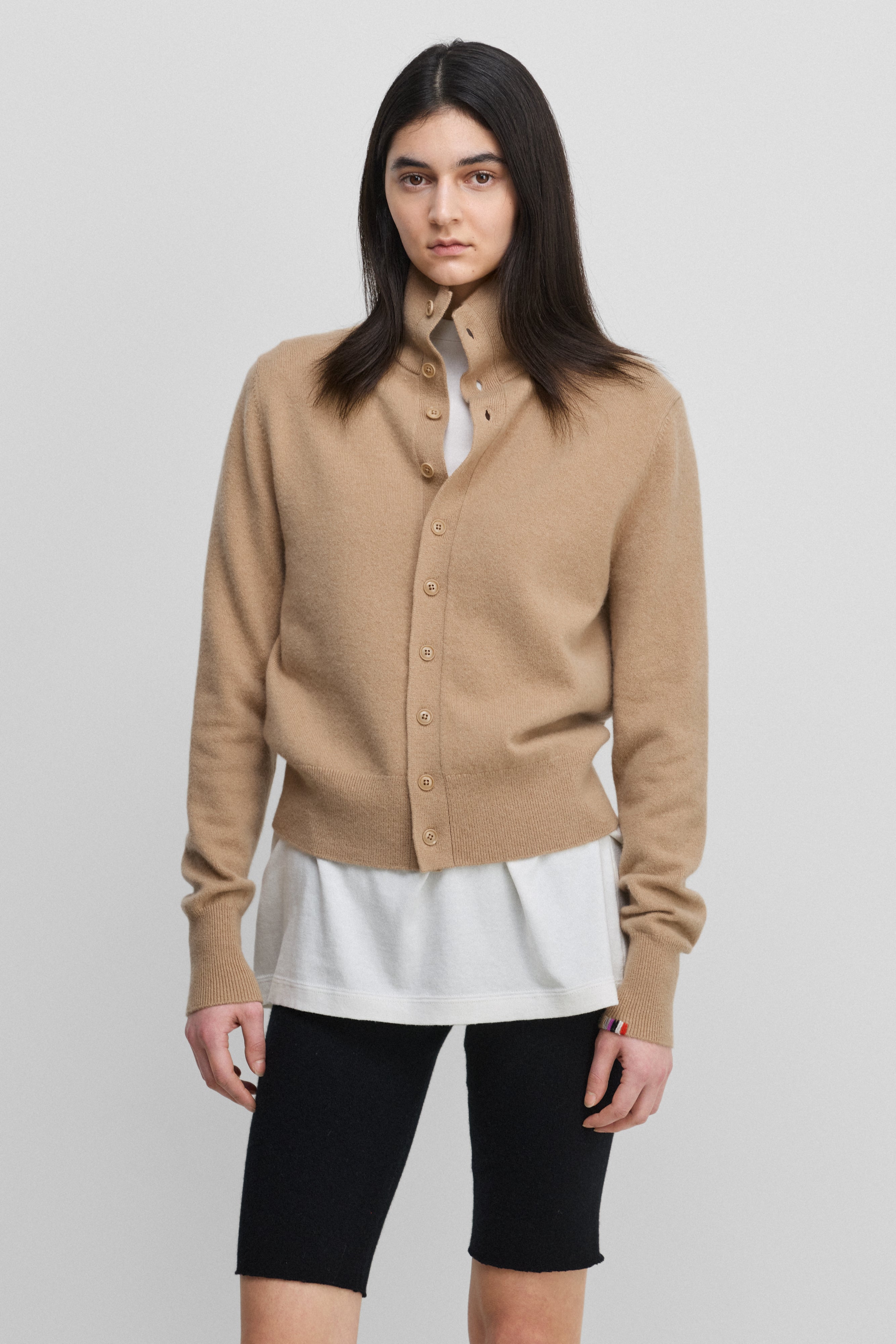 woman wearing a camel beige cashmere button-up cardigan with a rib-knitted collar.