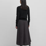 woman wearing a dark grey wool cashmere midi skirt, shown from the back.