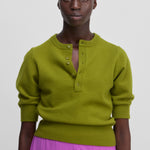 woman wearing a green half-button cashmere sweater with elbow-length sleeves and ribbed trims.