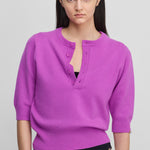 woman wearing a bright pink half-button cashmere sweater with elbow-length sleeves.