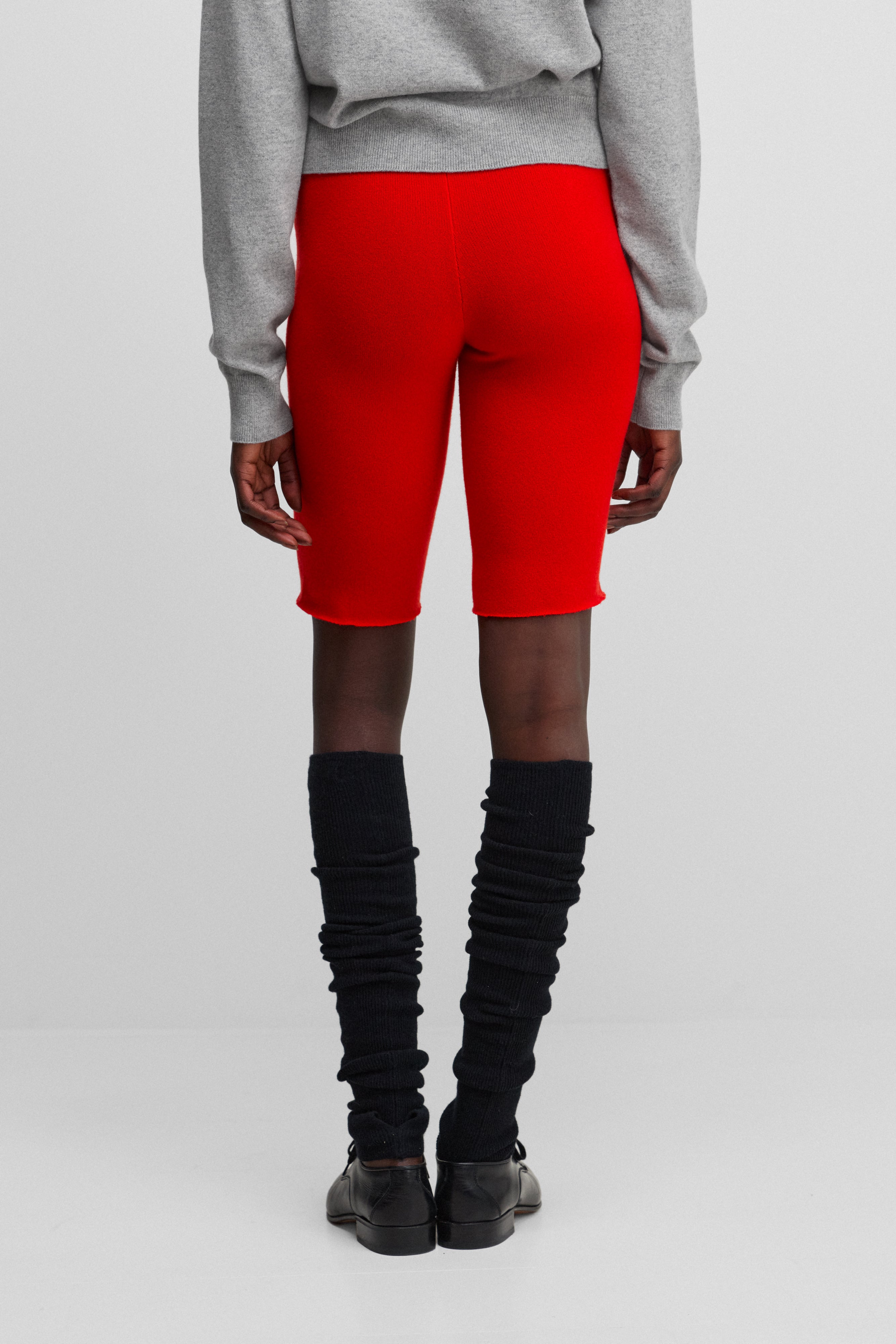 woman wearing bright red cashmere biker shorts with ribbed elasticated waistband, shown from the back.
