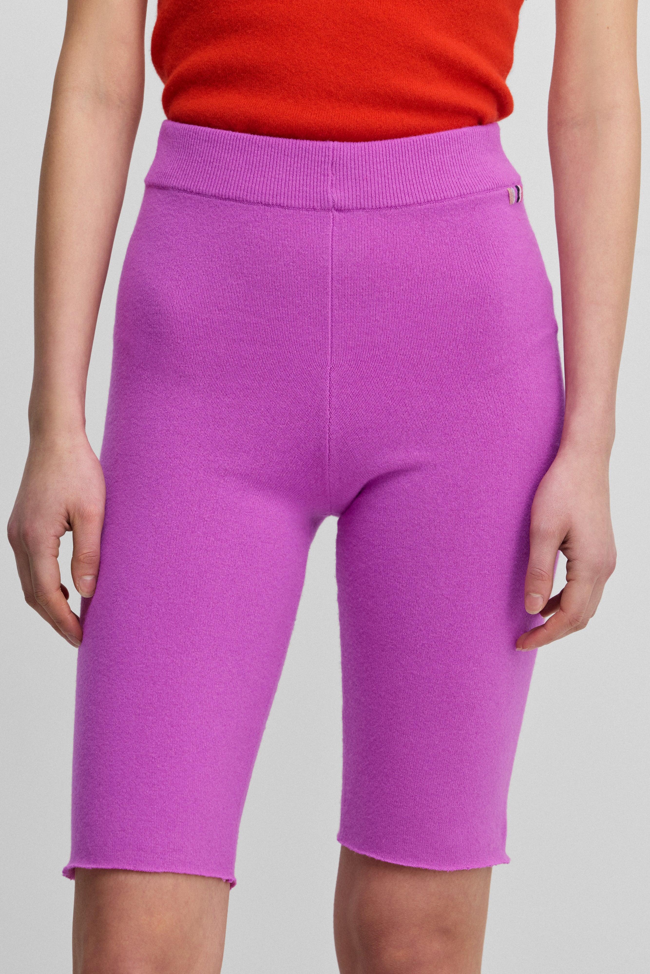 woman wearing bright pink cashmere biker shorts with ribbed elasticated waistband.