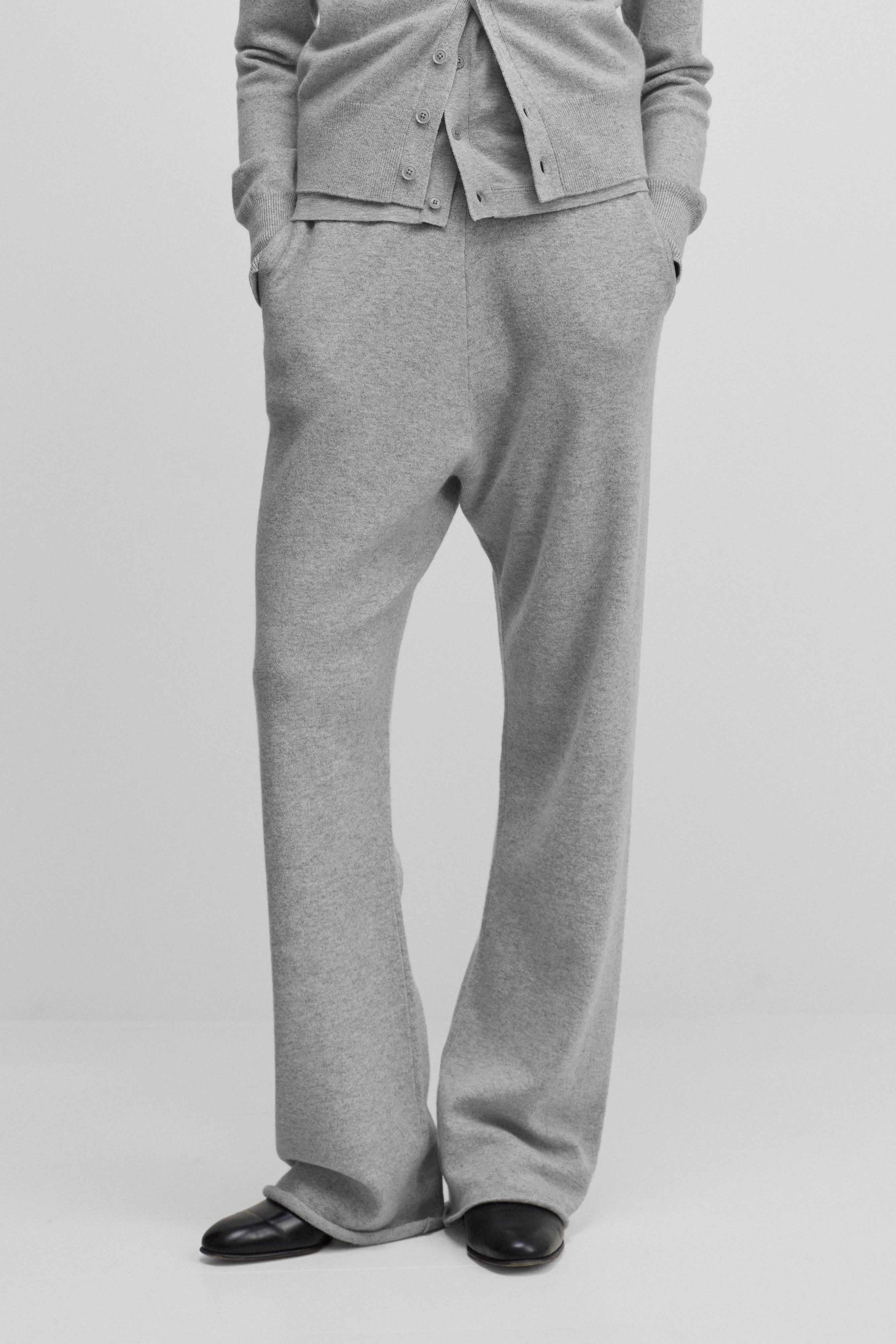 model wearing grey loose-fit cashmere pants with a drawstring waistband and side pockets.