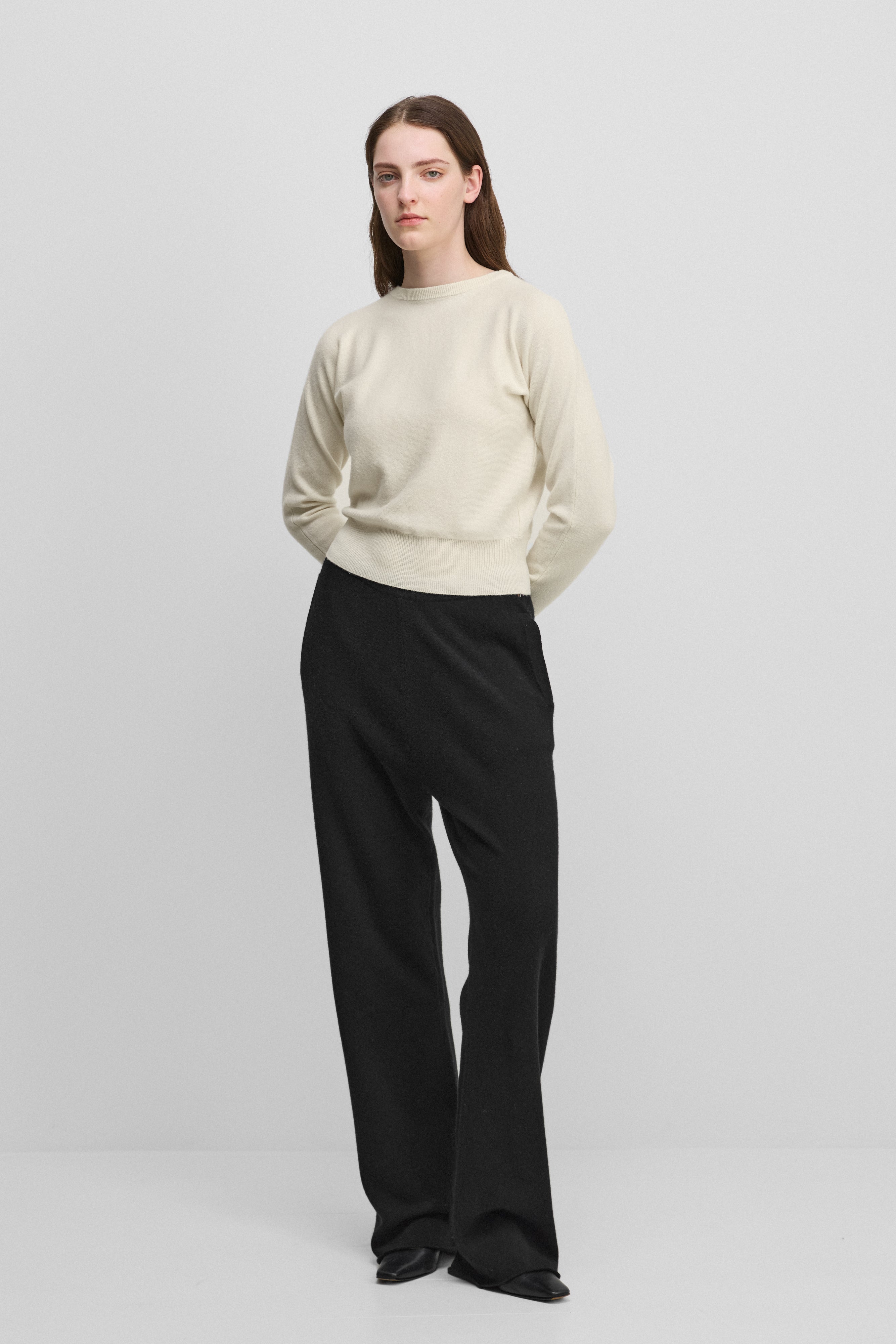 woman wearing black loose-fit cashmere pants with a drawstring waistband and side pockets.