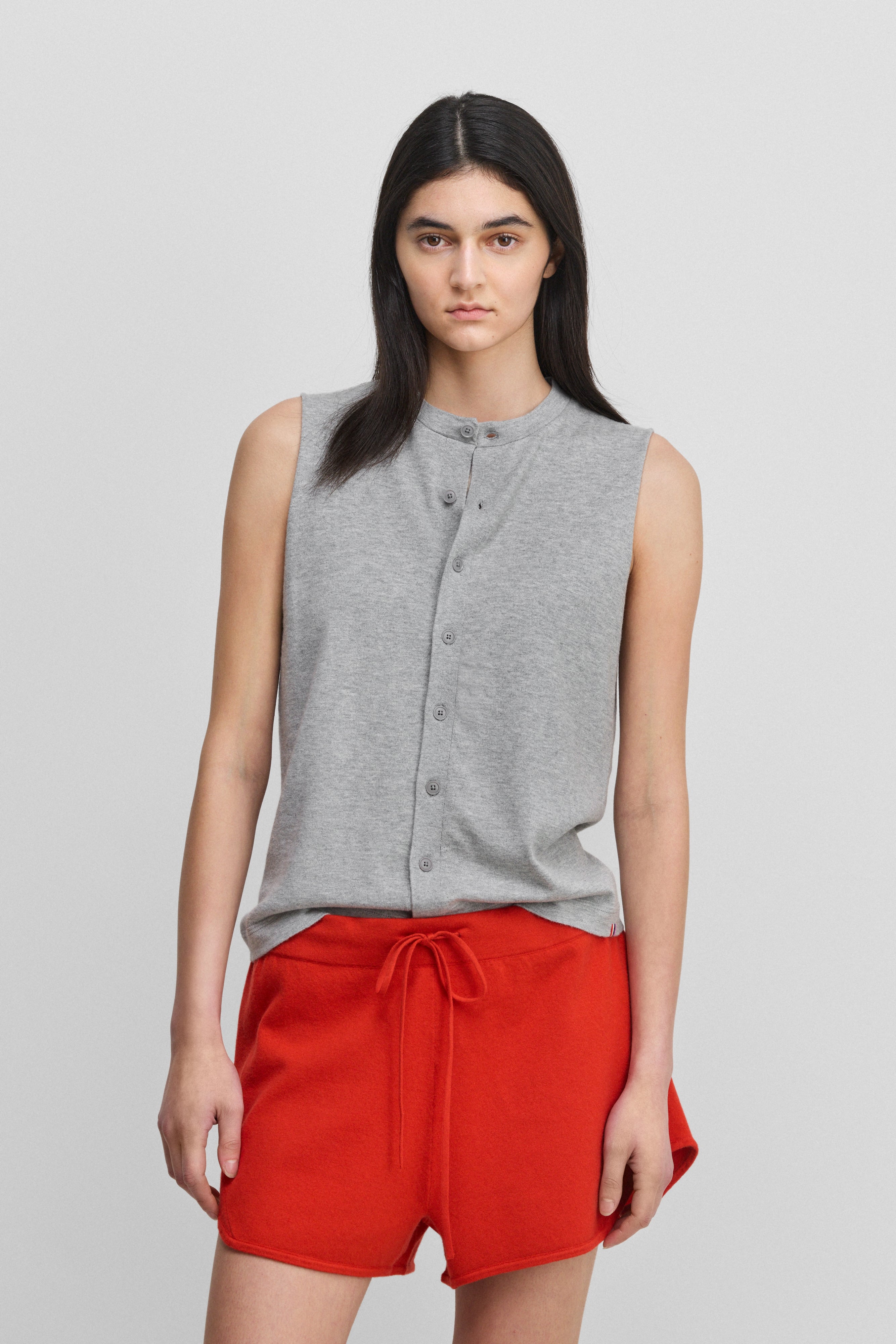 woman wearing a grey sleeveless cotton-cashmere vest with corozo buttons and a crewneck.