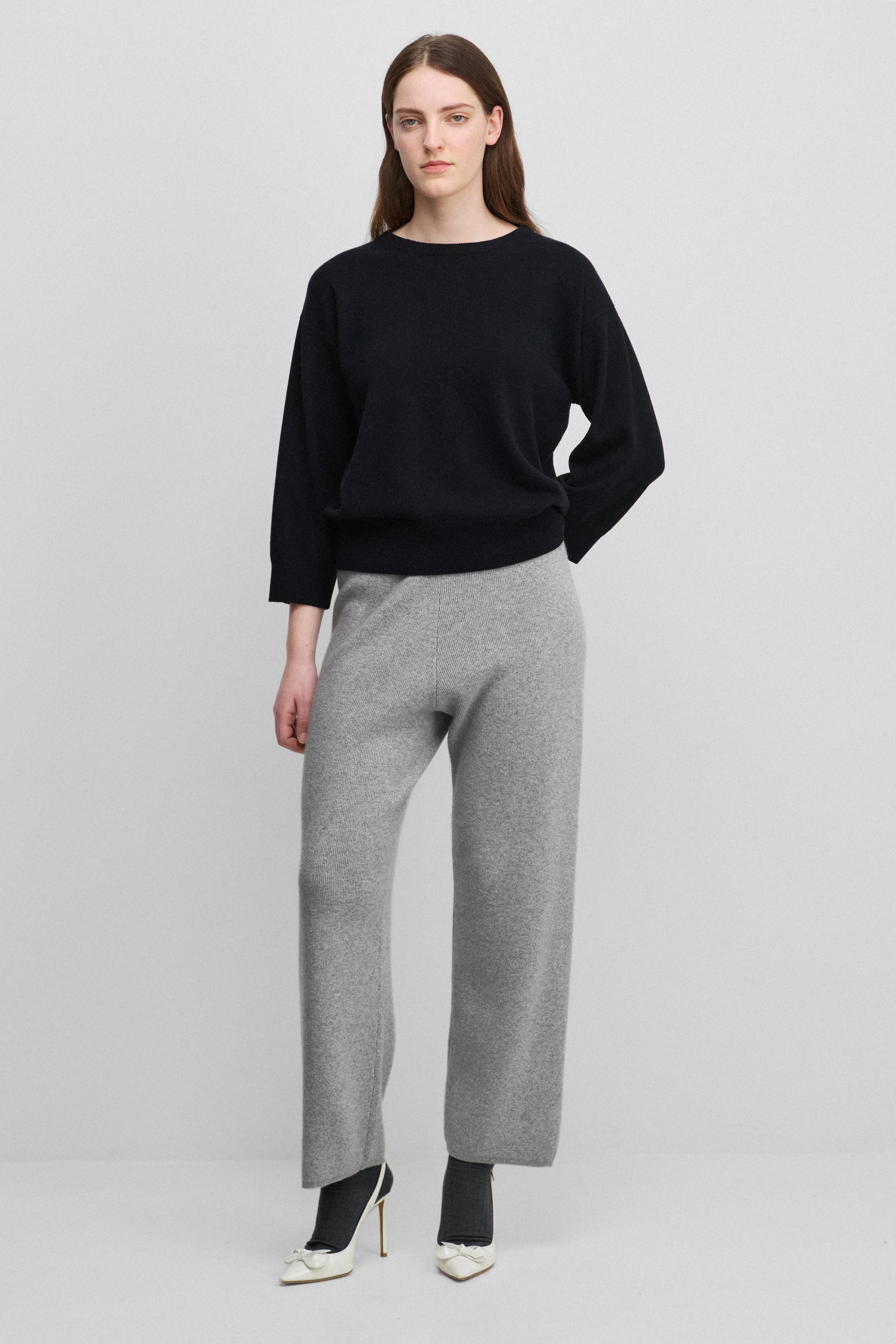 woman wearing light grey rib-knit cashmere pants with straight legs and a drawstring waist.