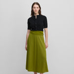 woman wearing a green flared wool cashmere midi skirt, styled with a black cardigan.