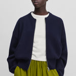 woman wearing a navy blue cashmere zip-up cardigan with crew neck and side pockets.